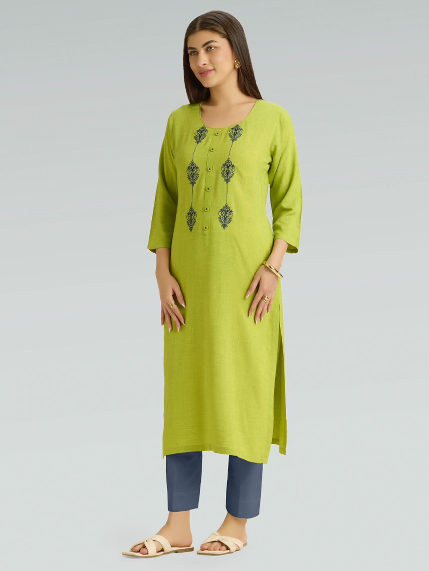 Woman wearing a green kurta with embroidery on a gray background