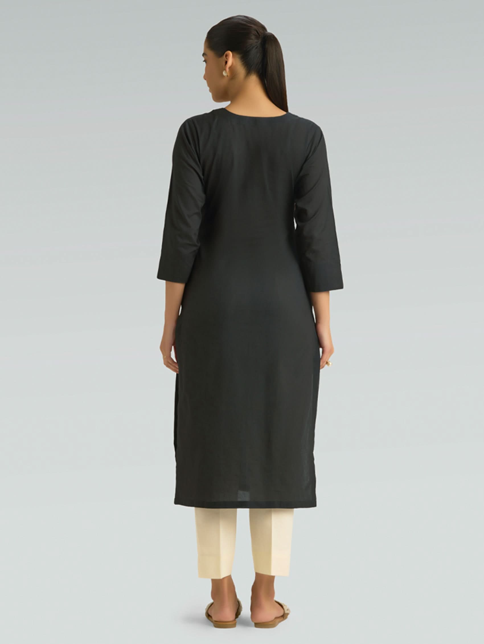 Woman wearing a black kurta with white pants on a light gray background