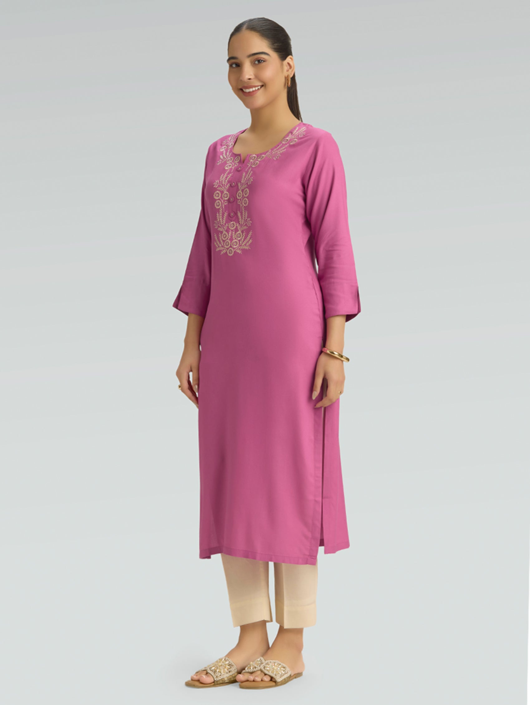 Woman wearing a pink kurta with embroidery on a gray background