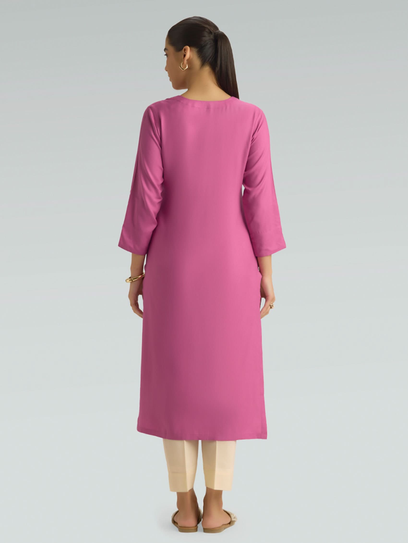 A woman is wearing a pink kurta for women, featuring a plain back design and a comfortable straight-fit silhouette.