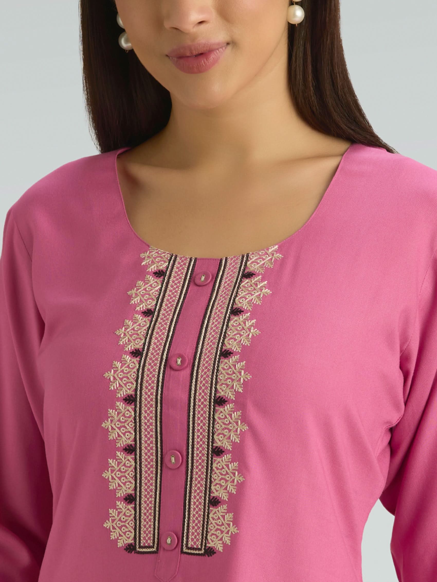 Close-up of a pink top with intricate embroidery on a grey background