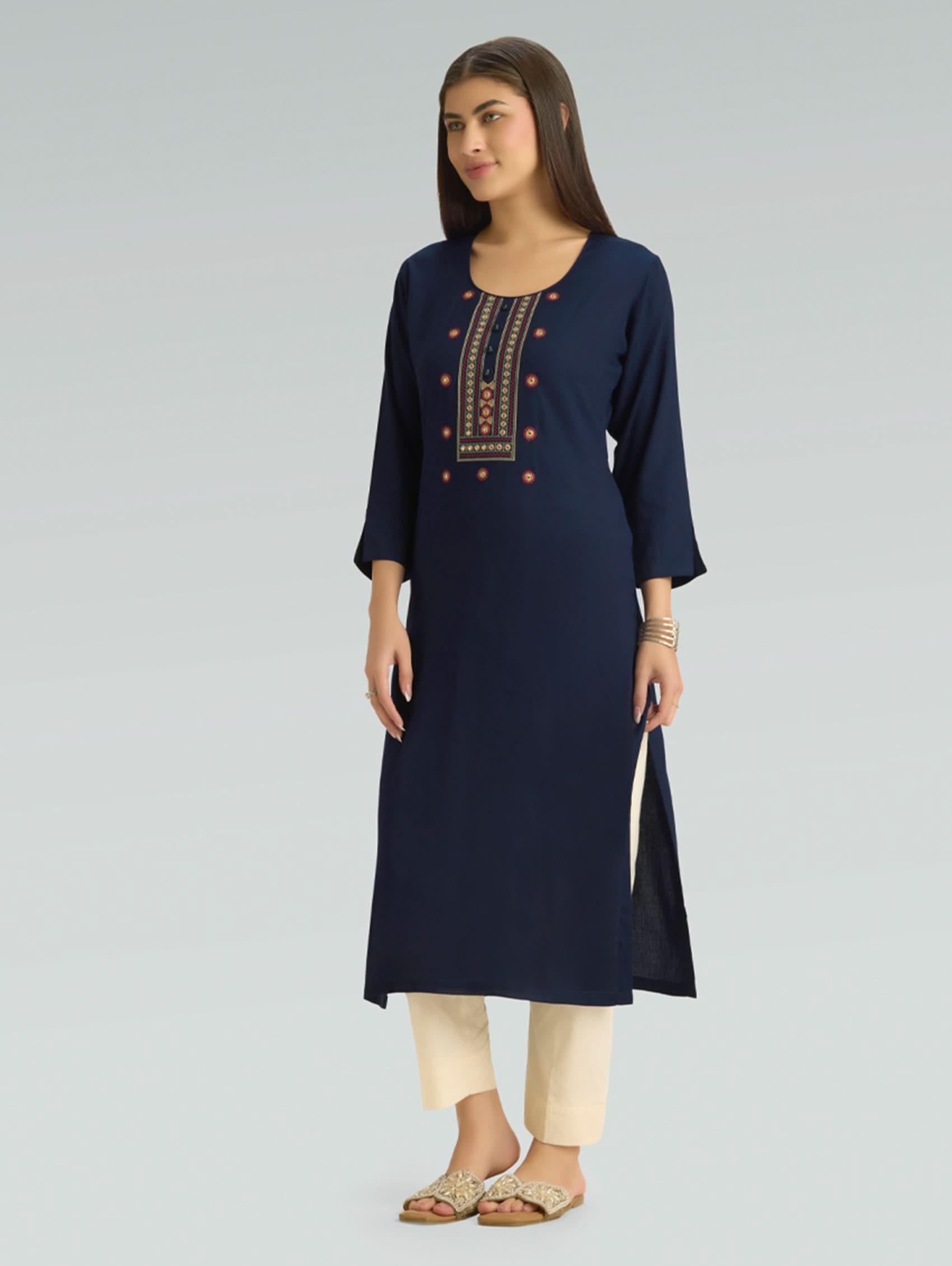 Woman wearing a navy blue kurta with embroidery on a gray background