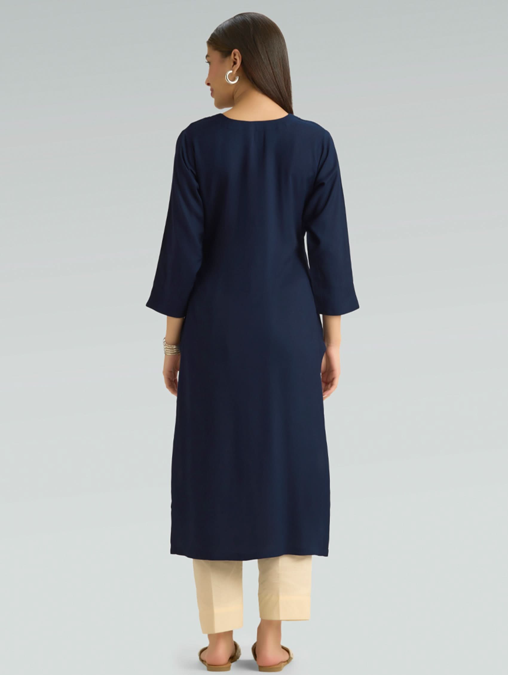 Woman wearing a navy blue kurta with beige pants on a light gray background