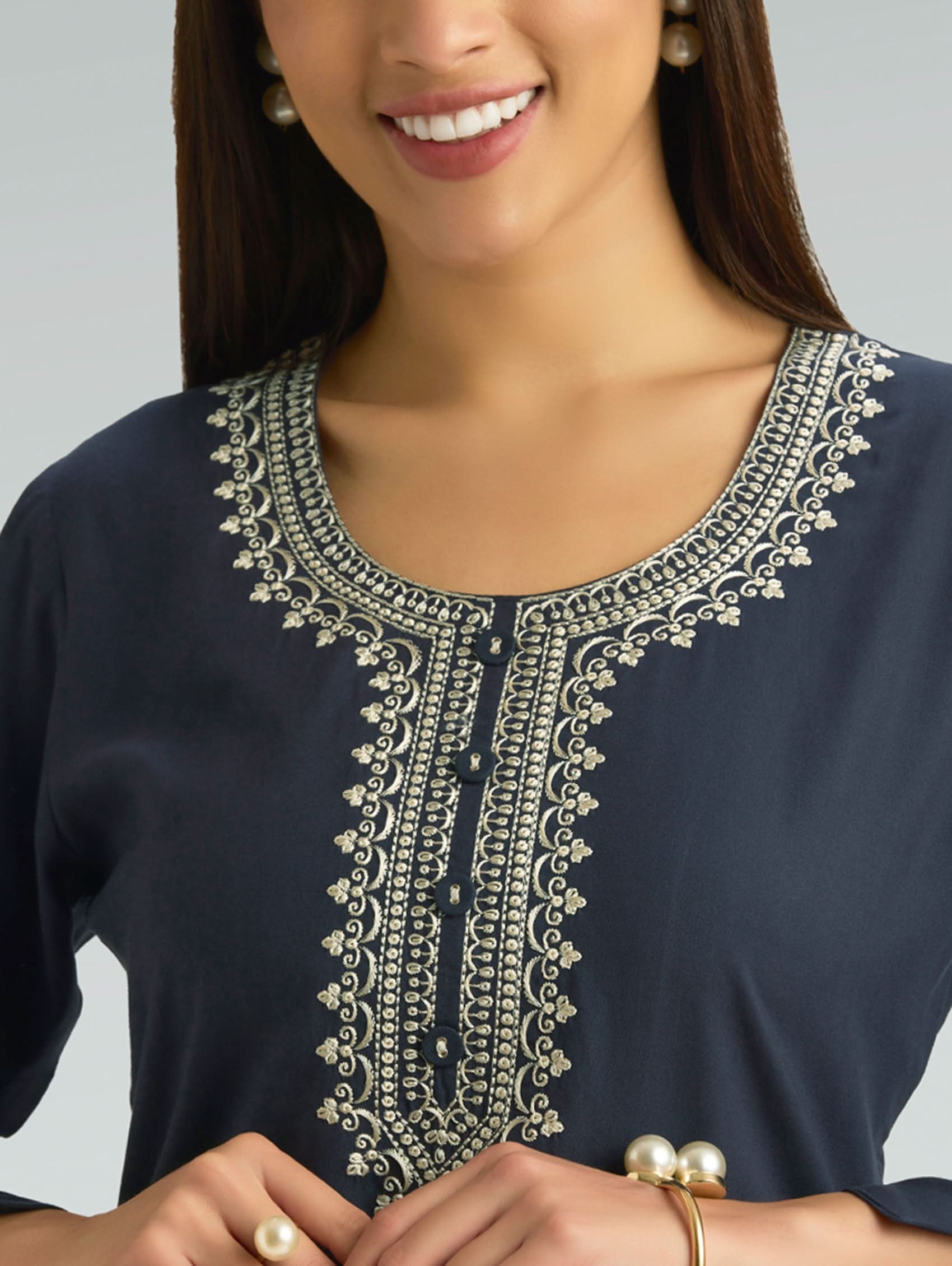Navy blue top with intricate white embroidery on a gray background