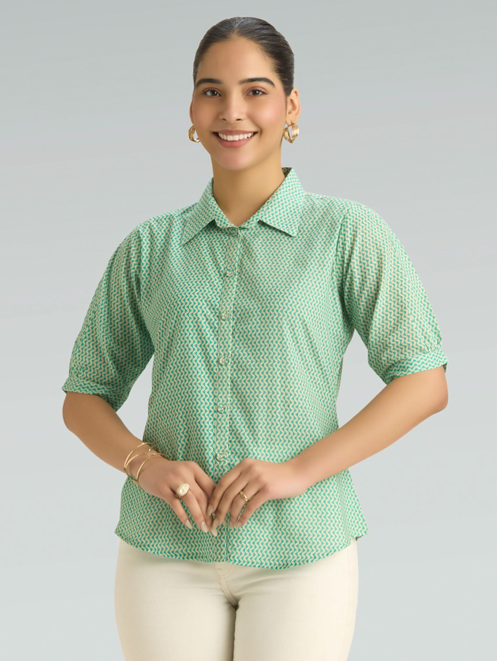 Woman wearing a green patterned shirt against a gray background