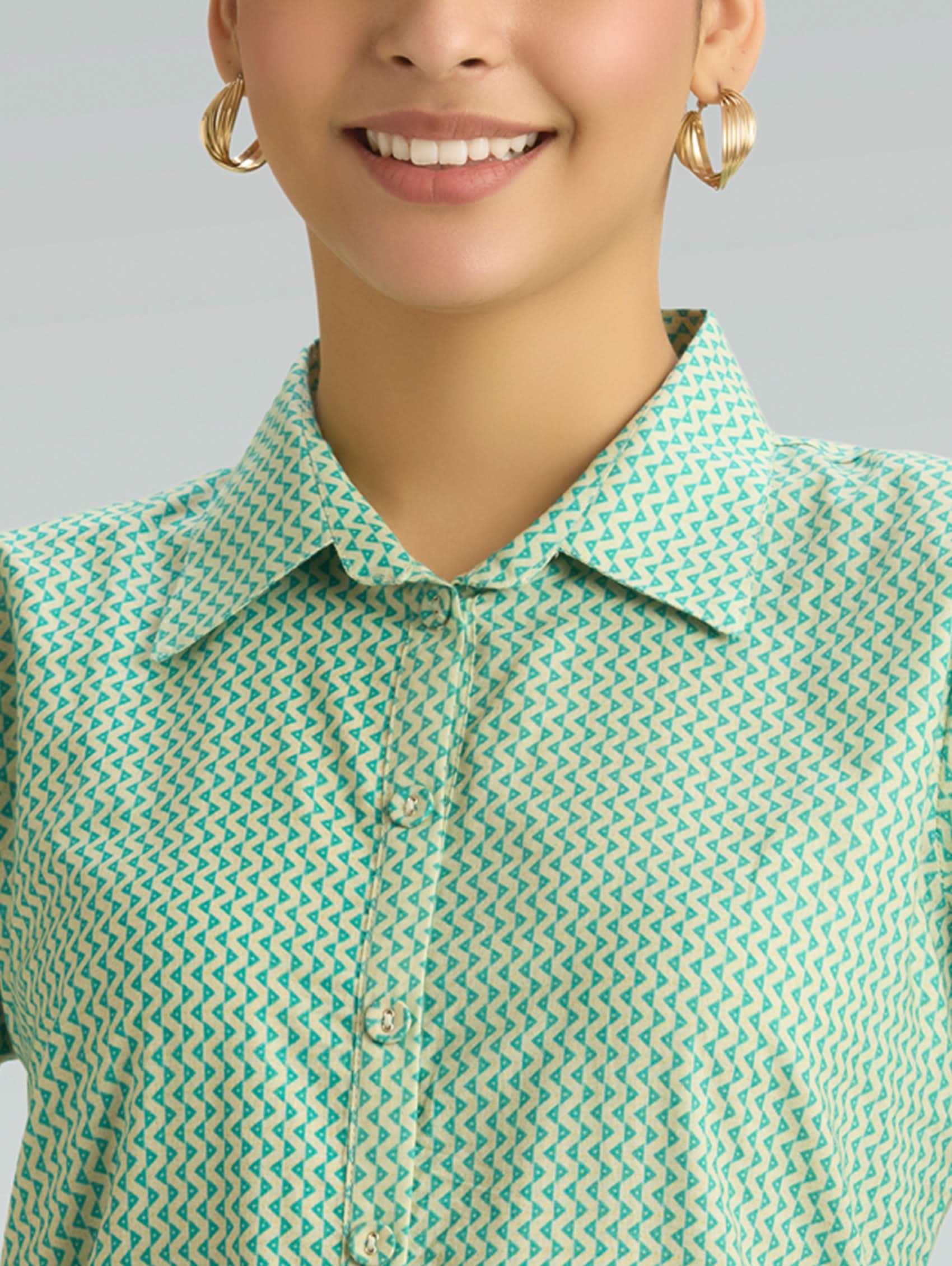Person wearing a green and white patterned shirt with a plain background