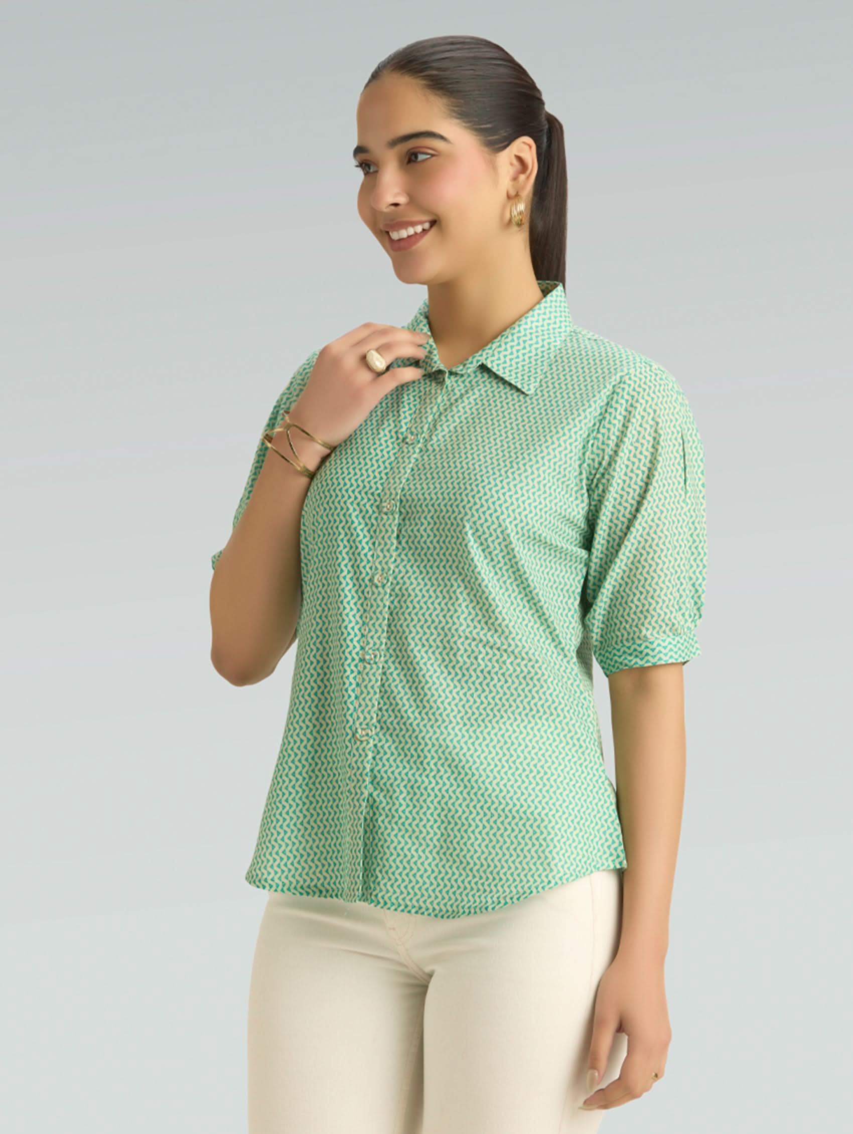 Woman wearing a green patterned shirt against a gray background