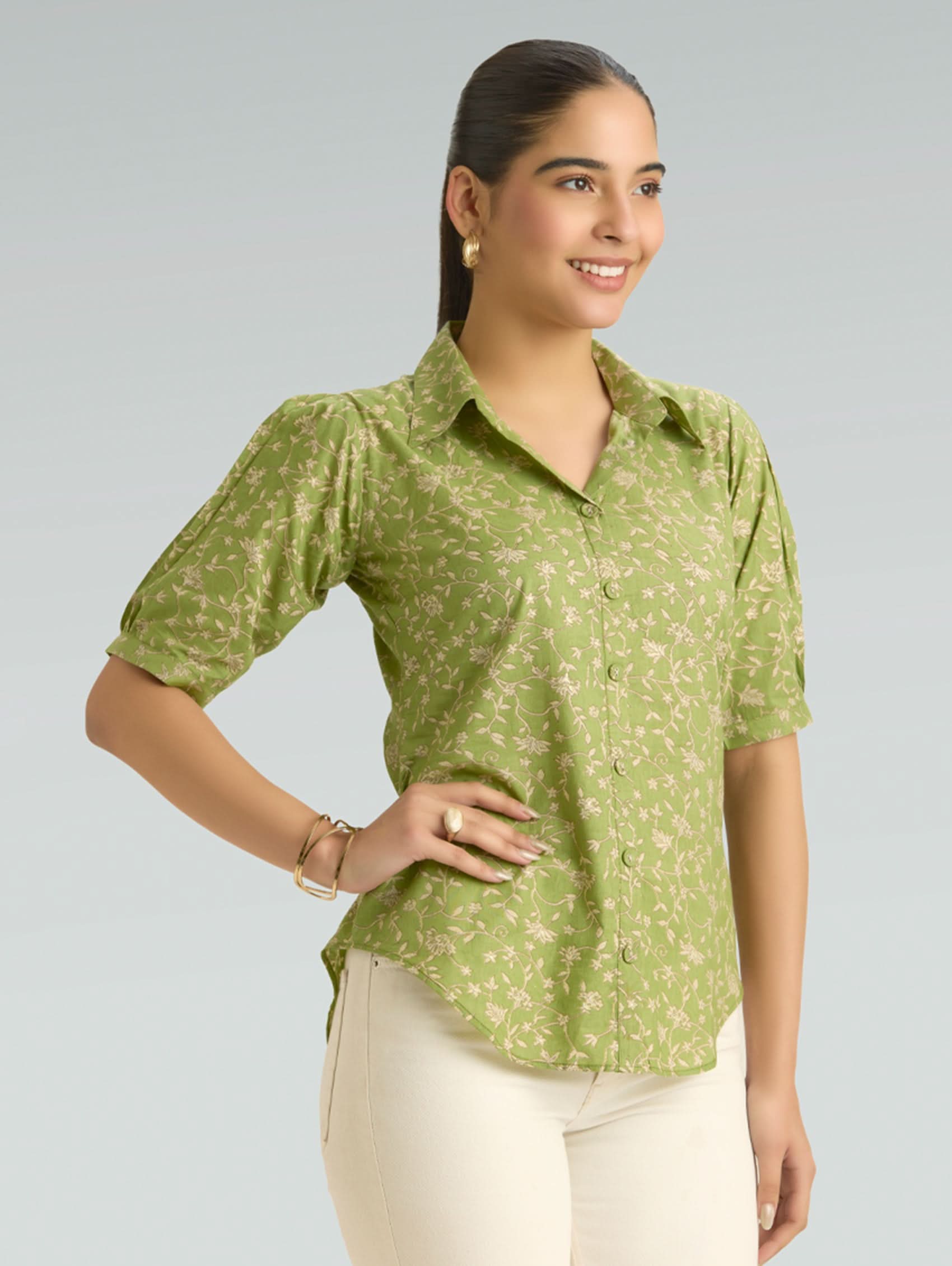 Woman wearing a green patterned shirt against a gray background