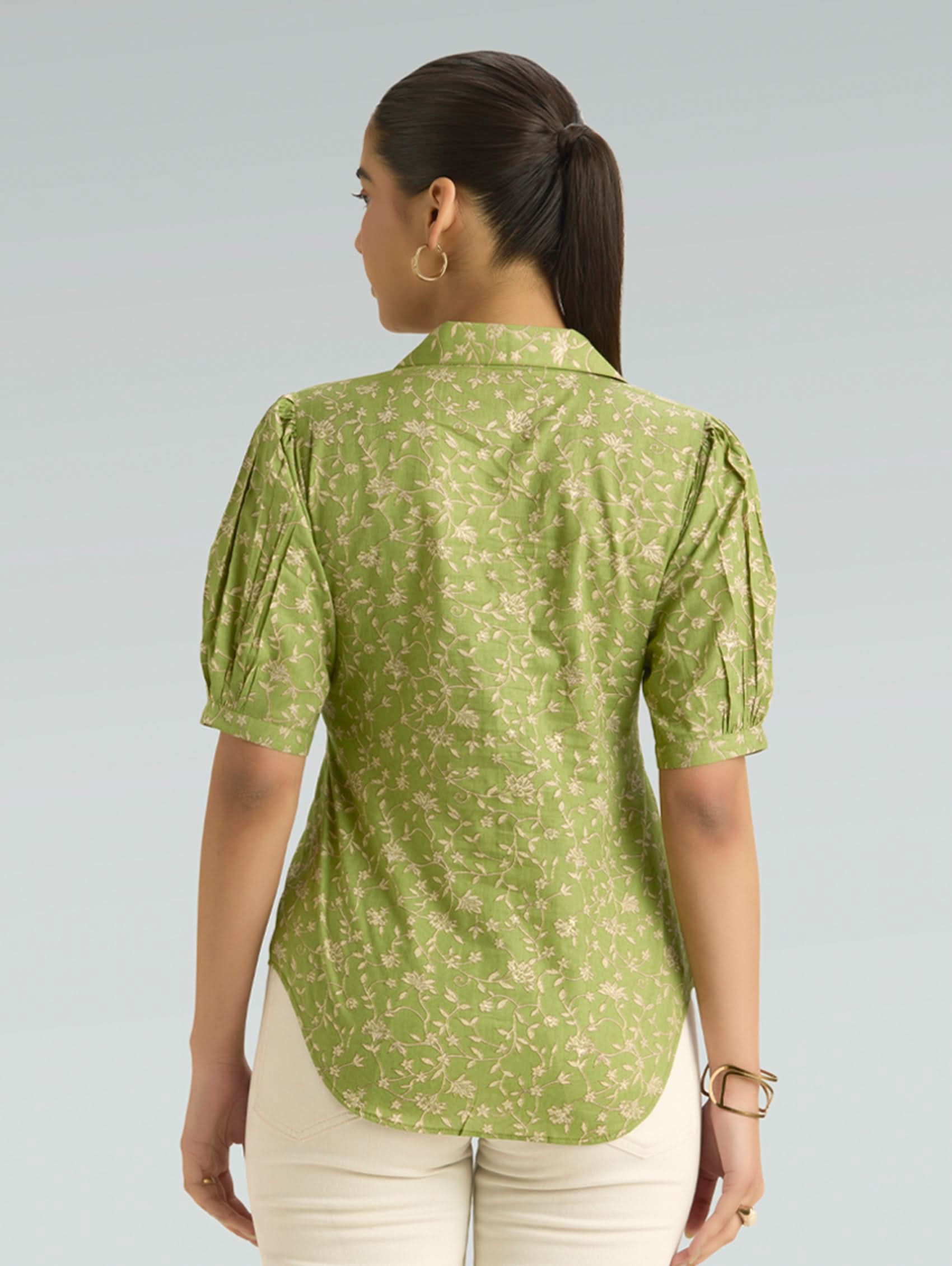Woman wearing a green floral blouse against a light gray background
