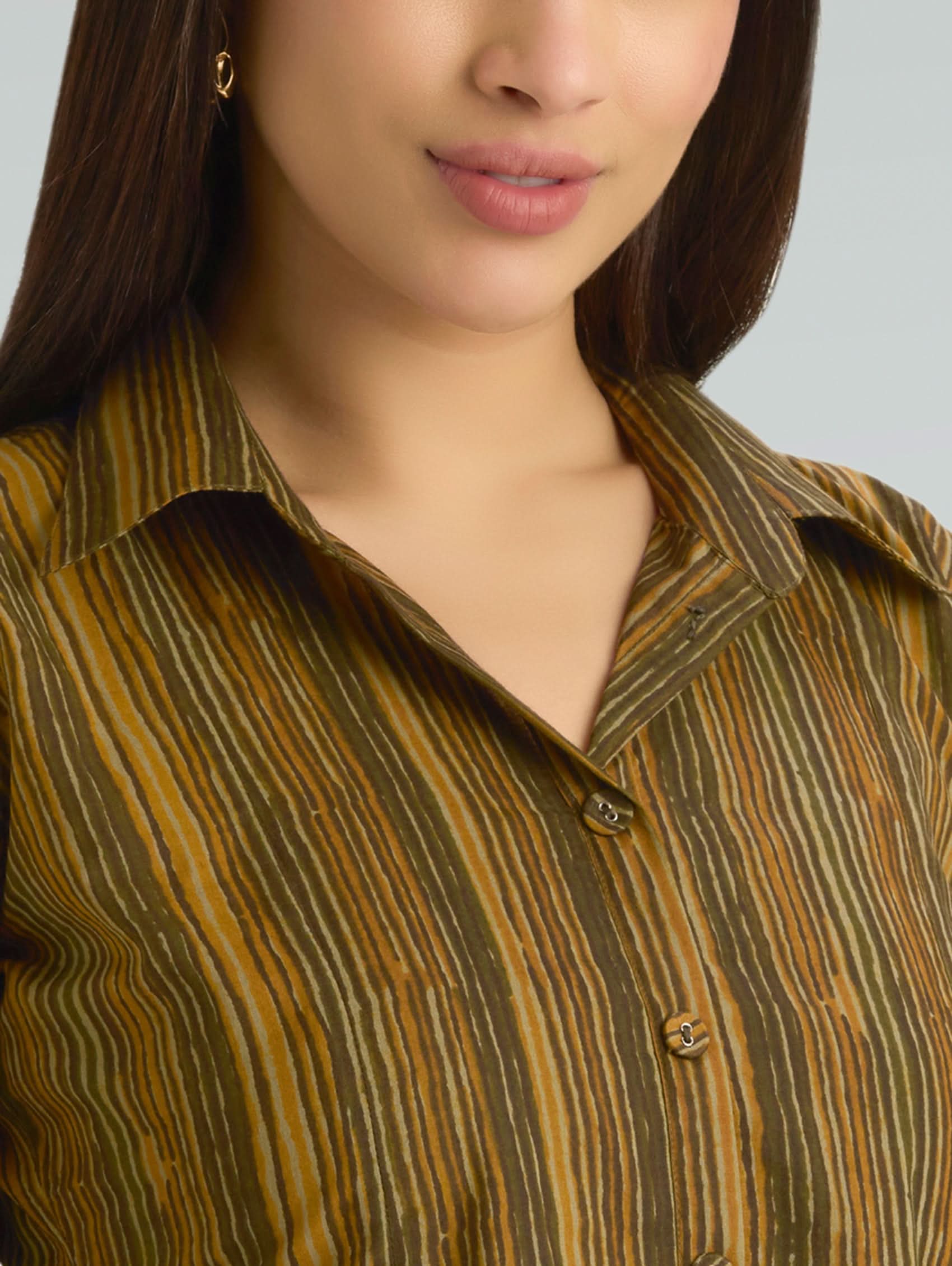 Close-up of a person wearing a patterned shirt with a neutral background