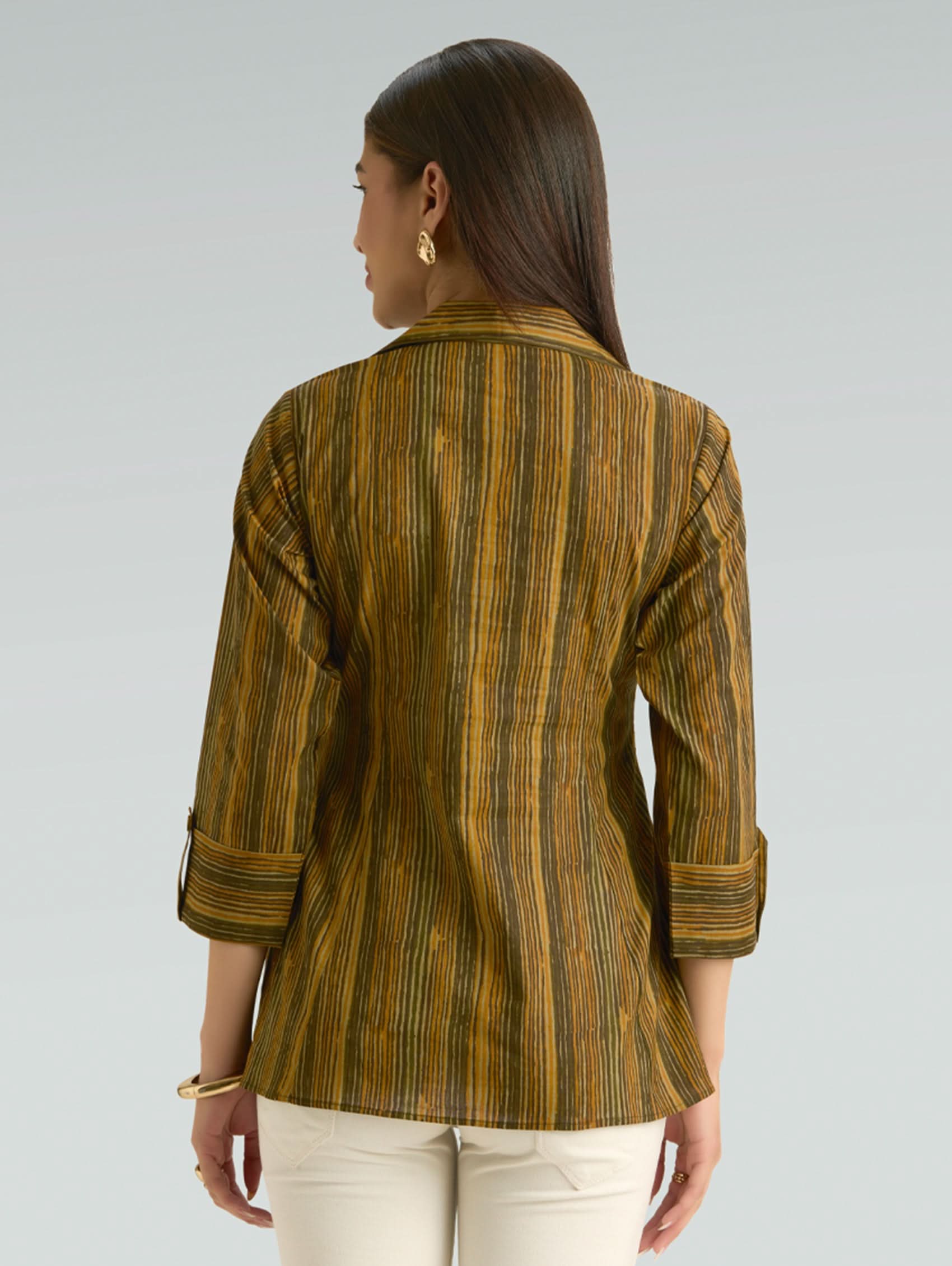 Woman wearing a striped brown shirt against a gray background