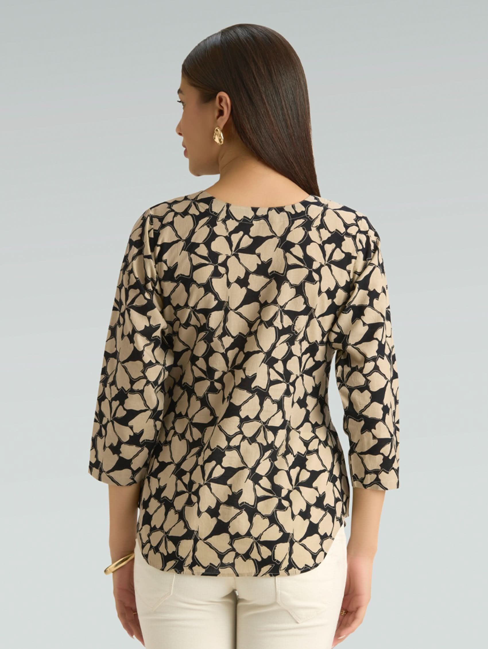 Woman wearing a patterned blouse with long sleeves on a plain background