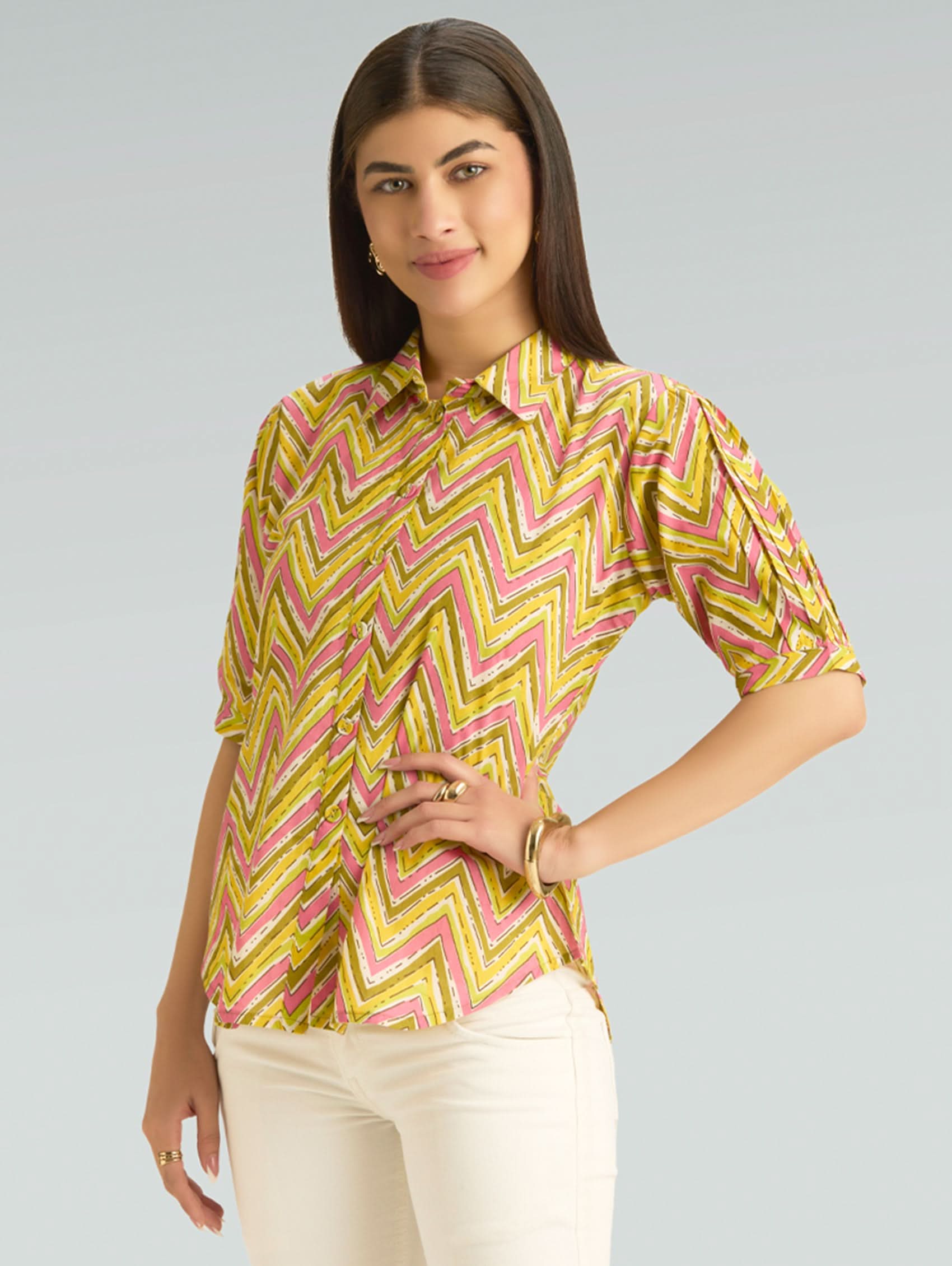 Woman wearing a yellow and pink chevron patterned shirt on a gray background