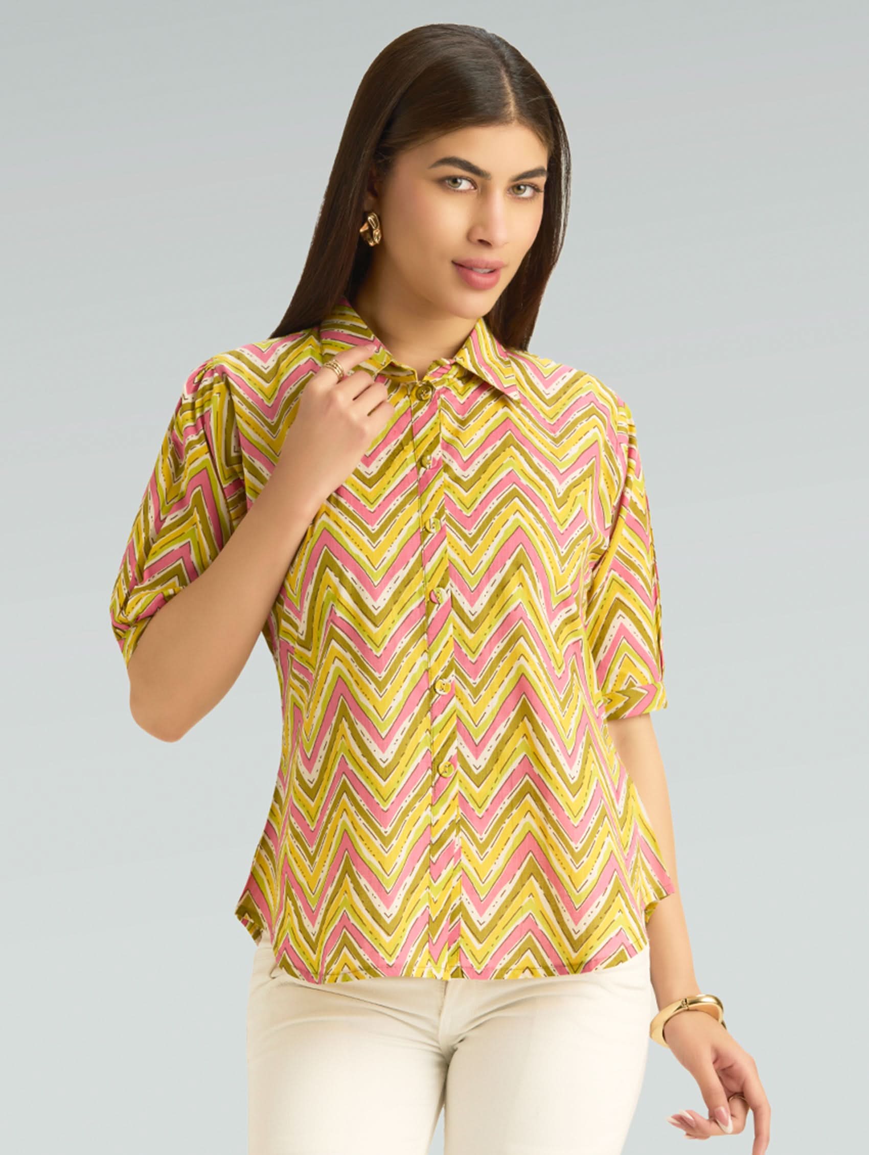 Woman wearing a yellow and pink patterned blouse against a gray background
