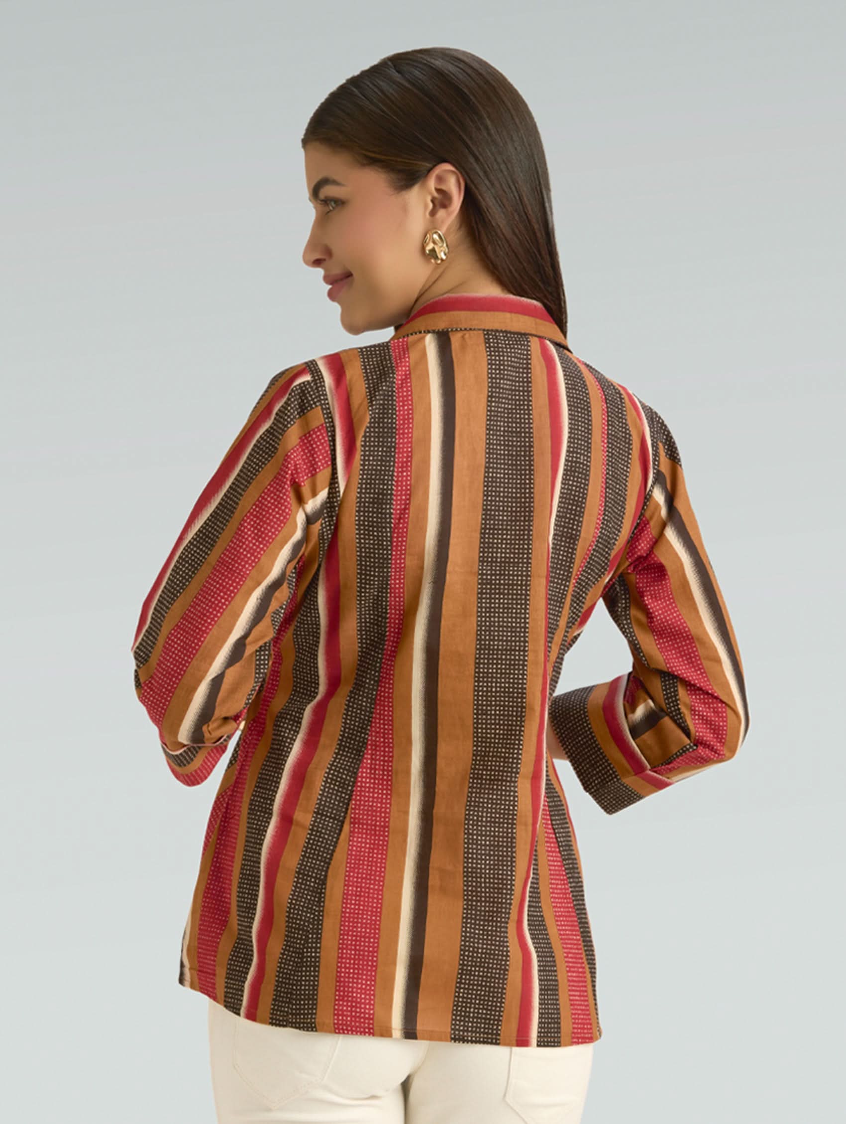 Woman wearing a colorful striped jacket on a plain background