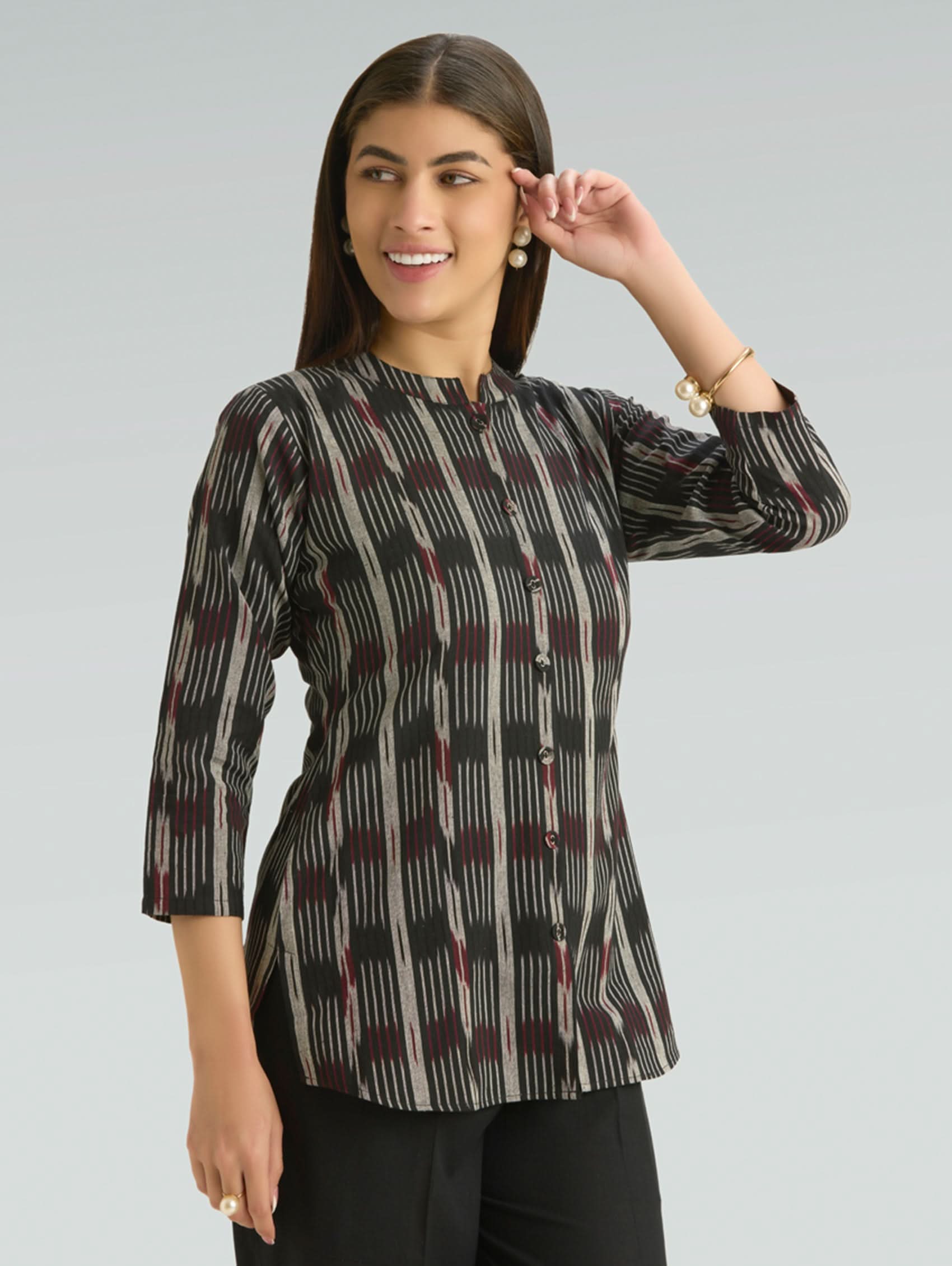 Woman wearing a patterned top against a plain background
