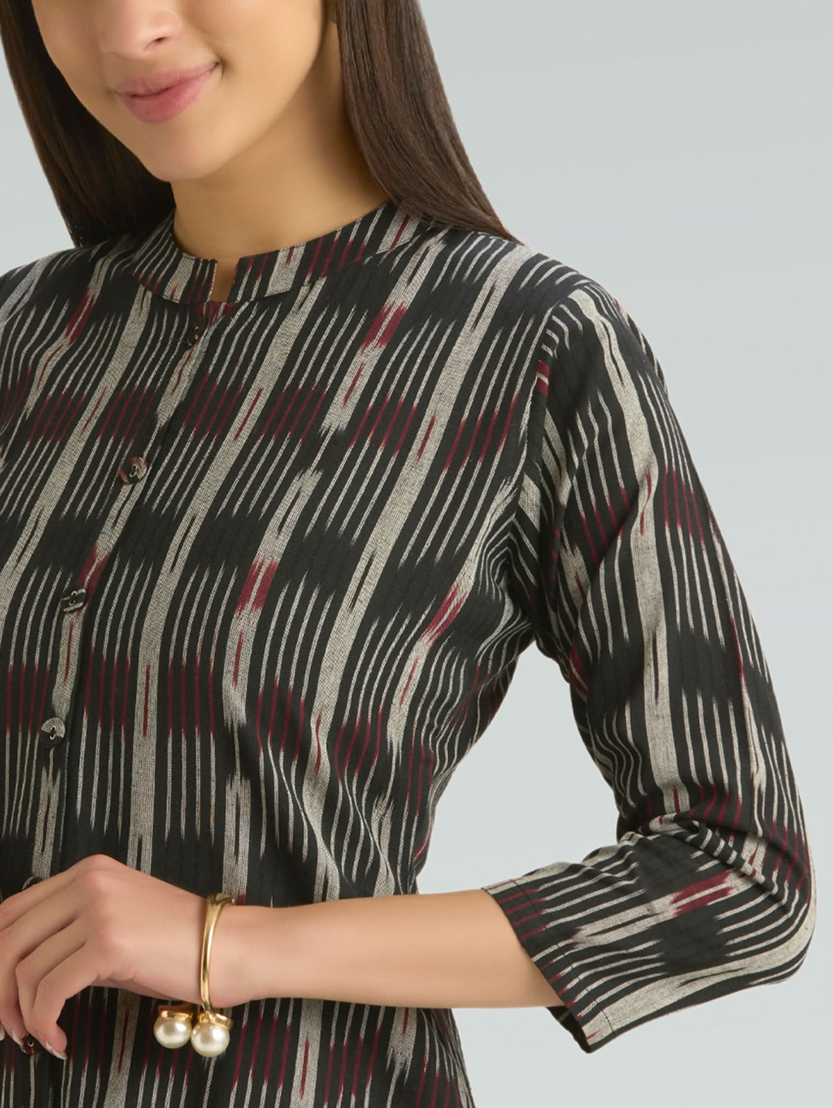 Woman wearing a black and white patterned top with a plain background