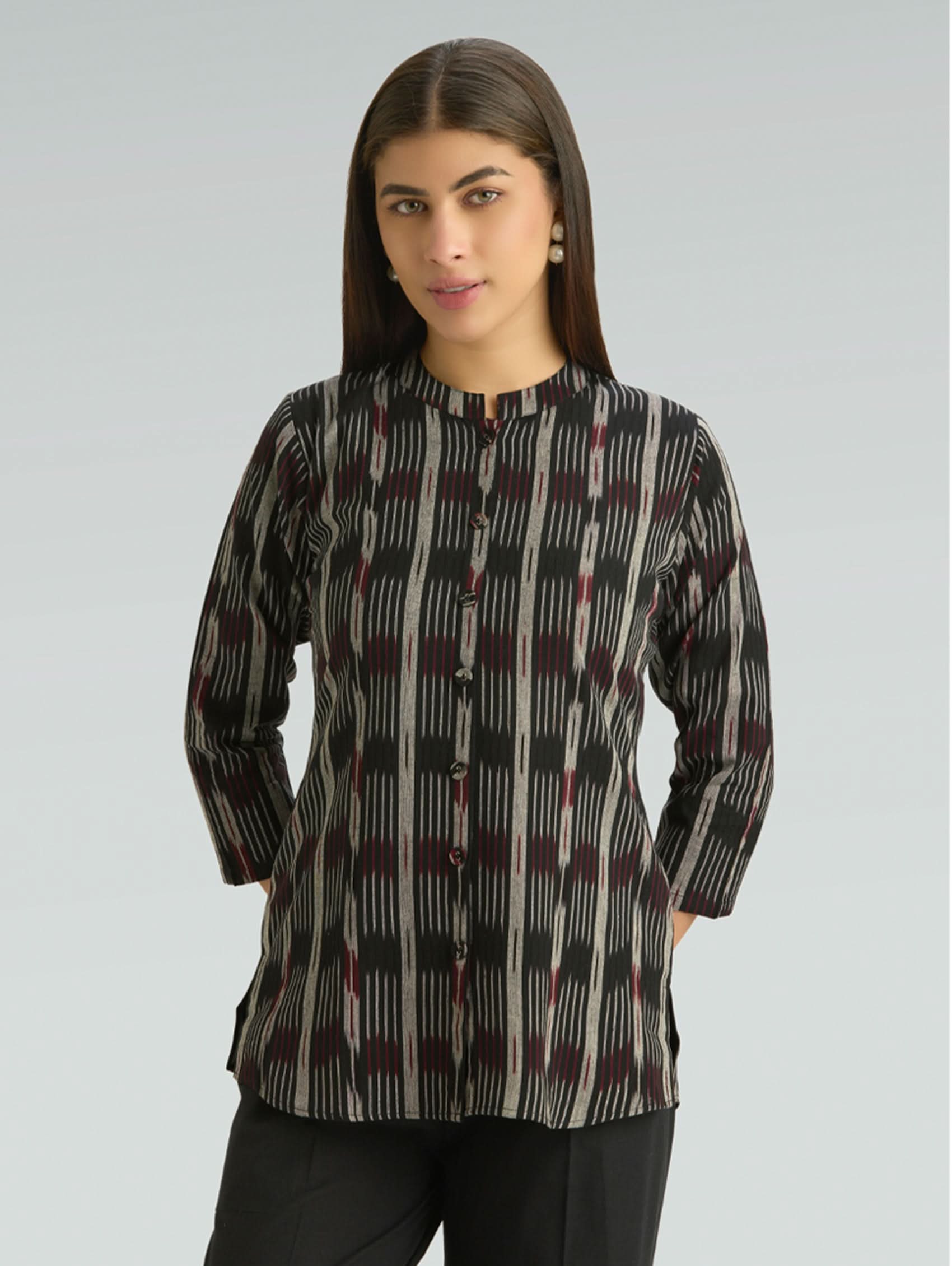 Woman wearing a patterned shirt against a gray background