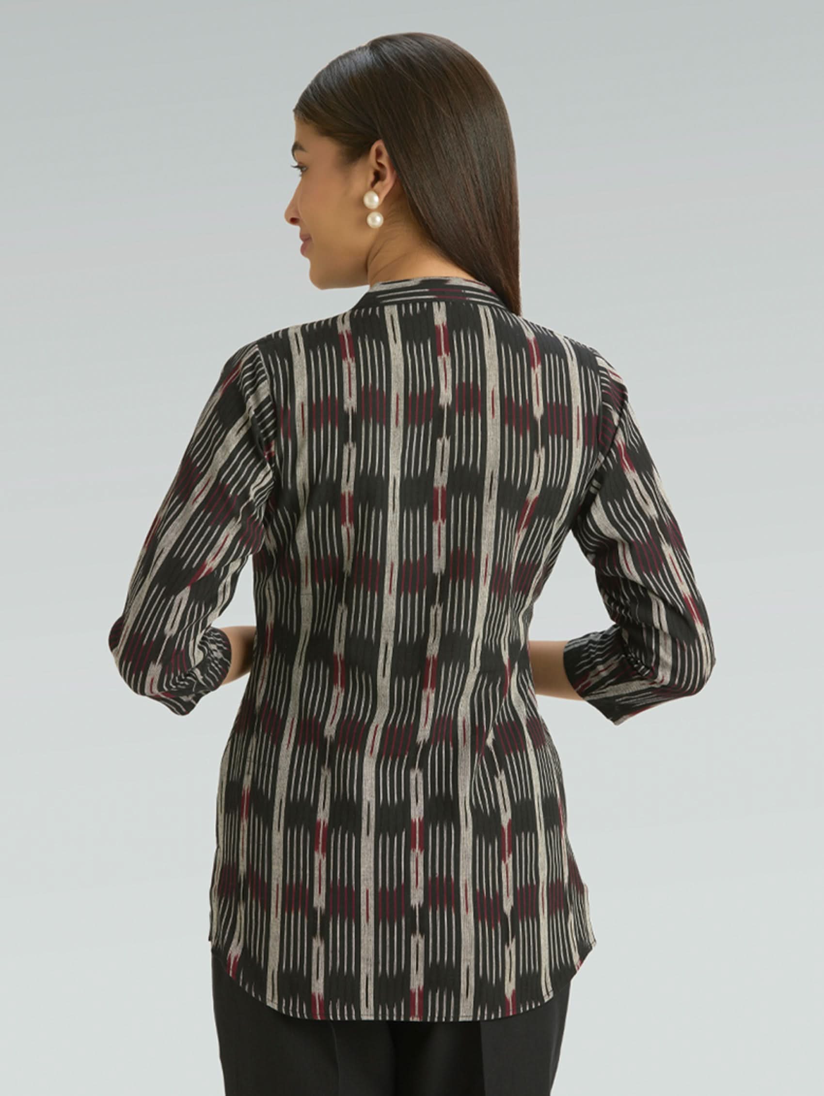 Woman wearing a patterned blouse against a plain background