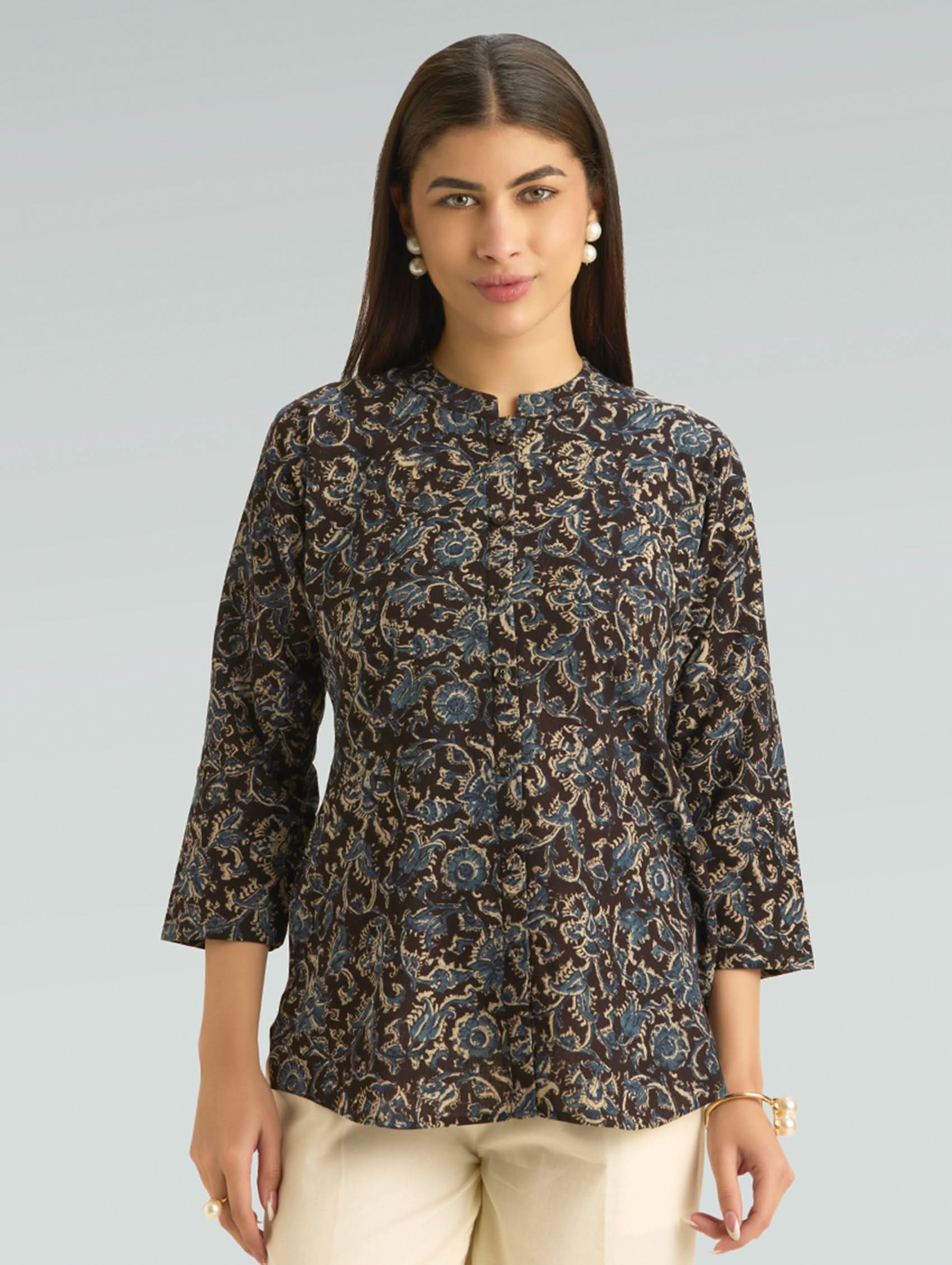 Woman wearing a patterned brown top against a gray background