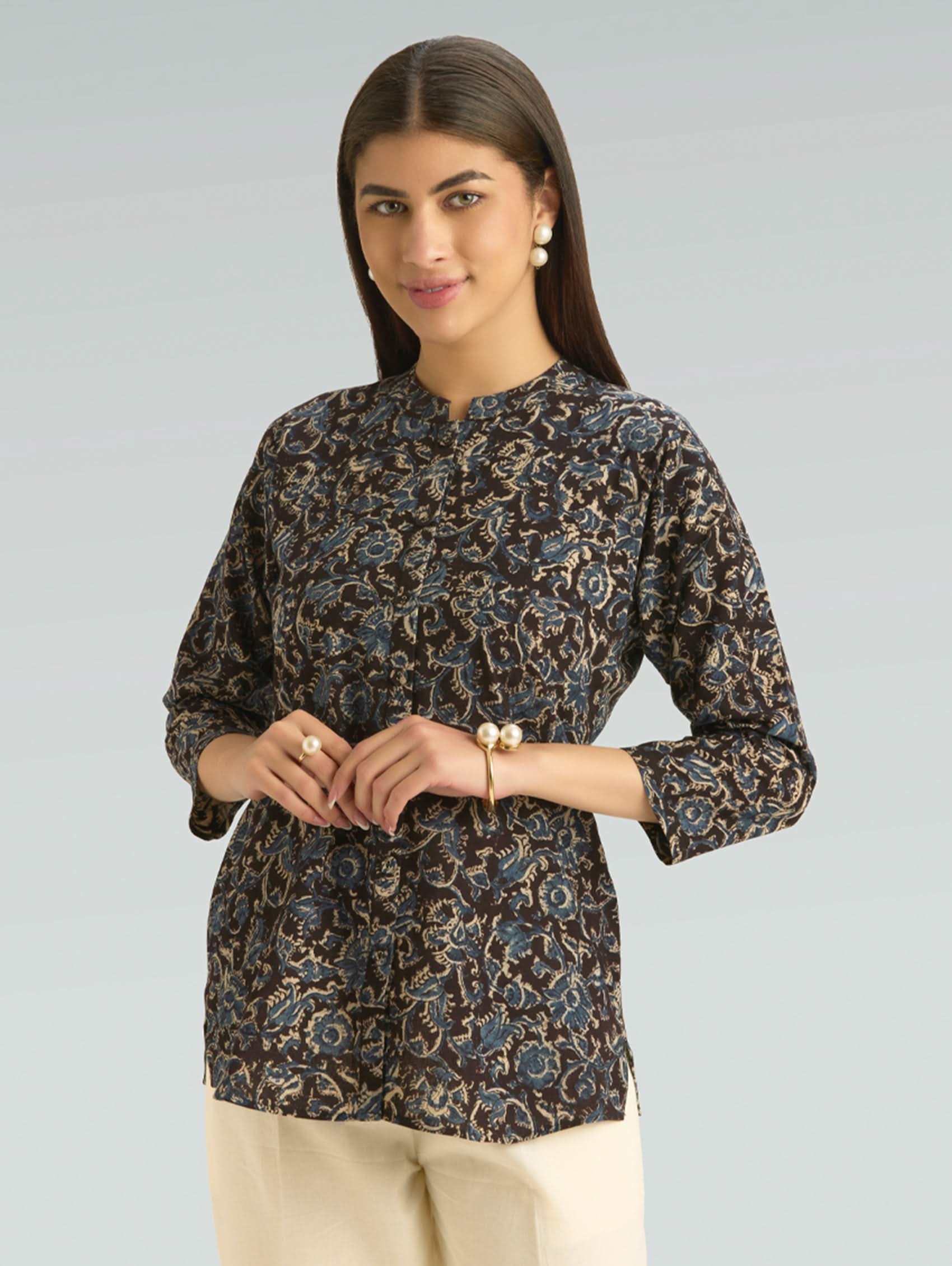 Woman wearing a patterned blouse against a plain background