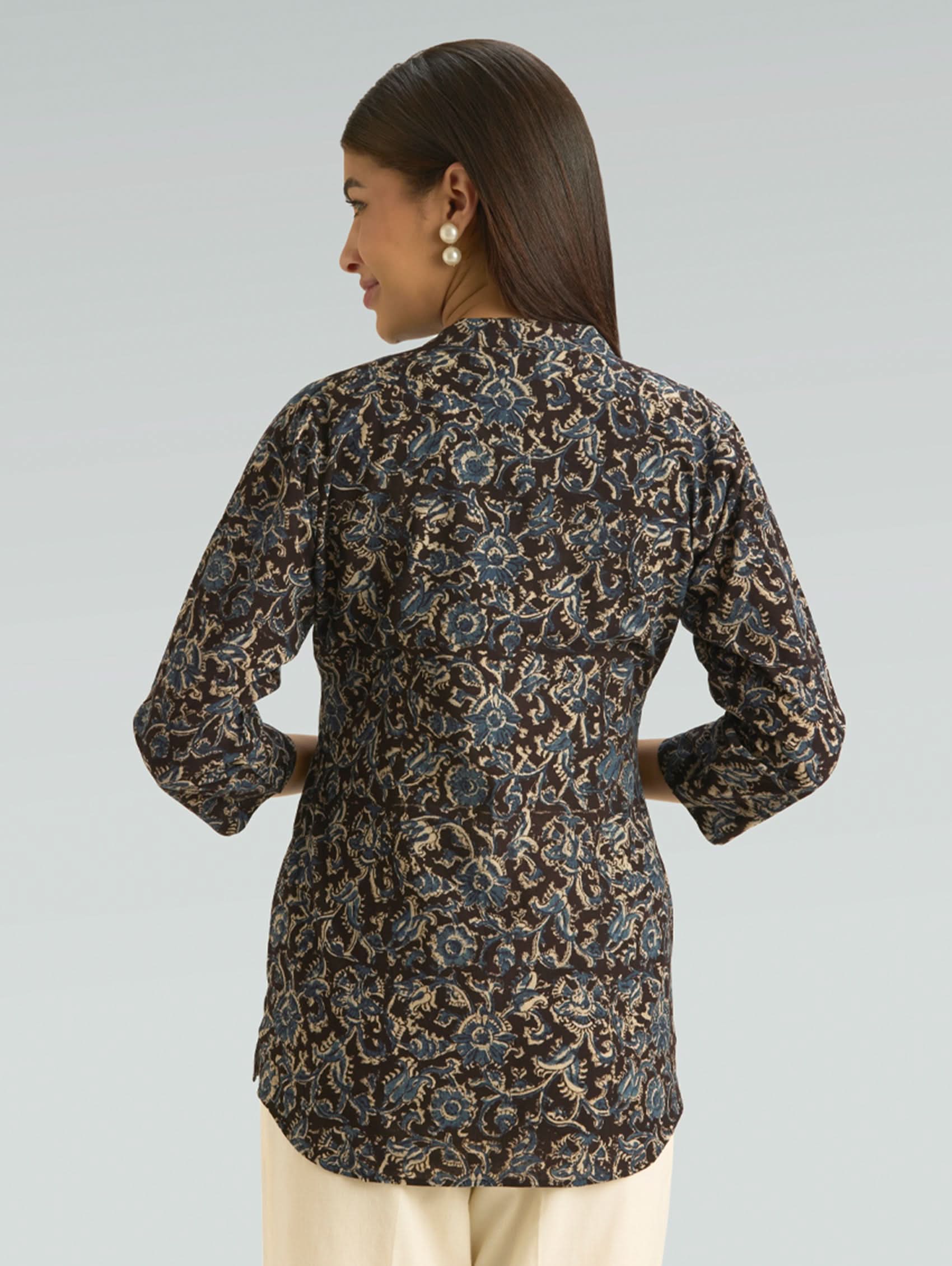 Woman wearing a patterned shirt against a plain background