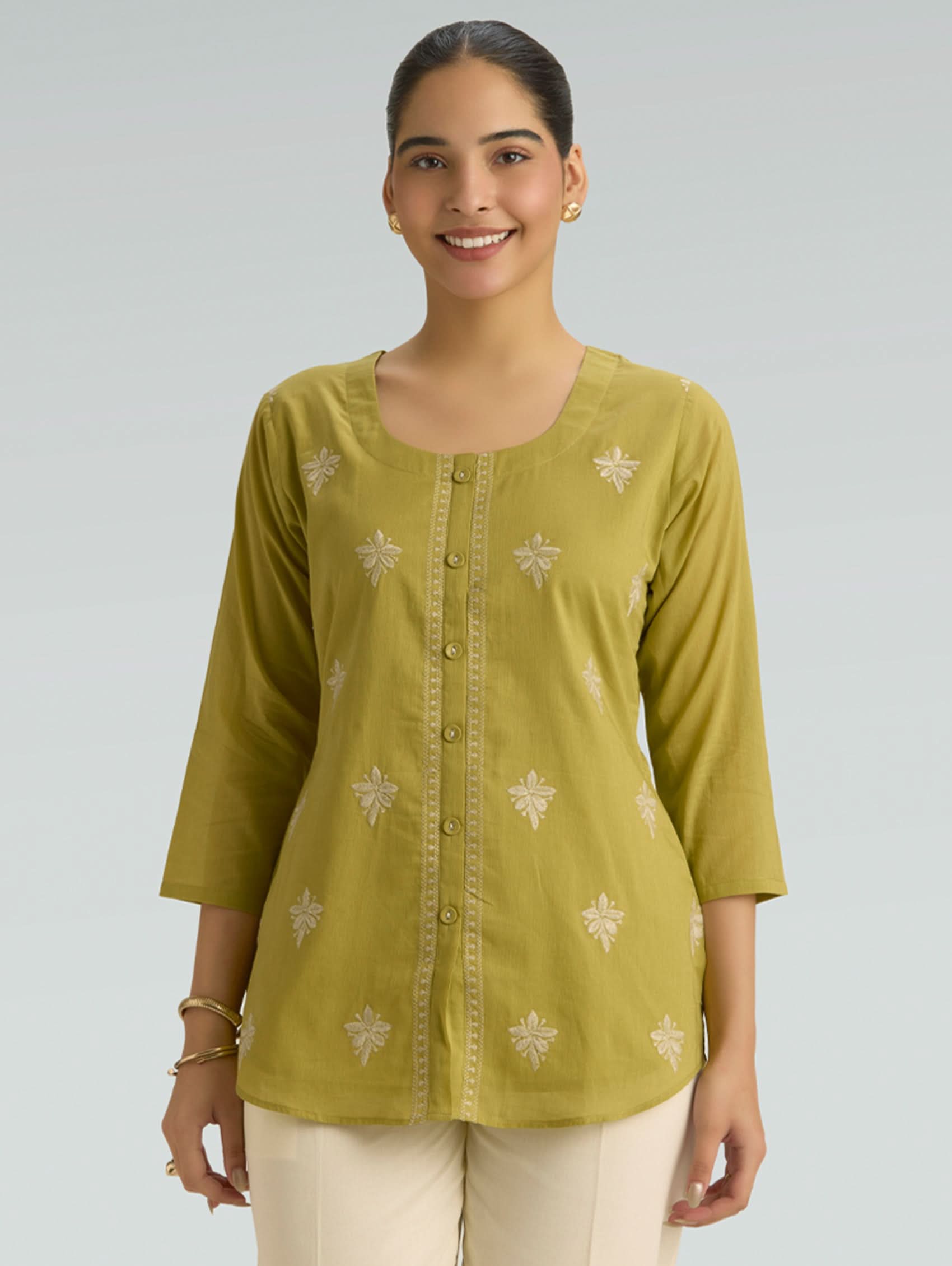 Woman wearing a green top with a plain background