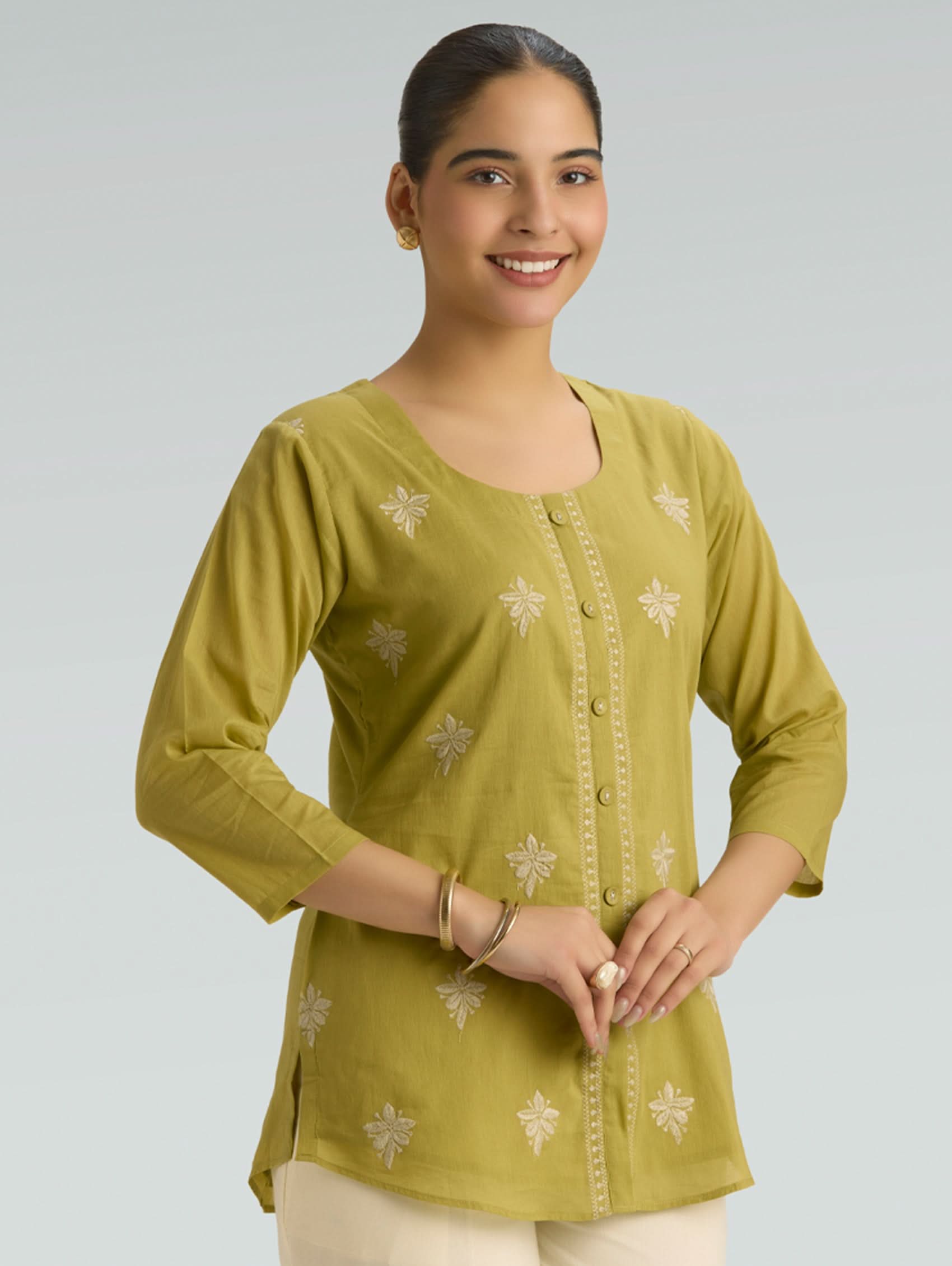 Woman wearing a green top with a plain background