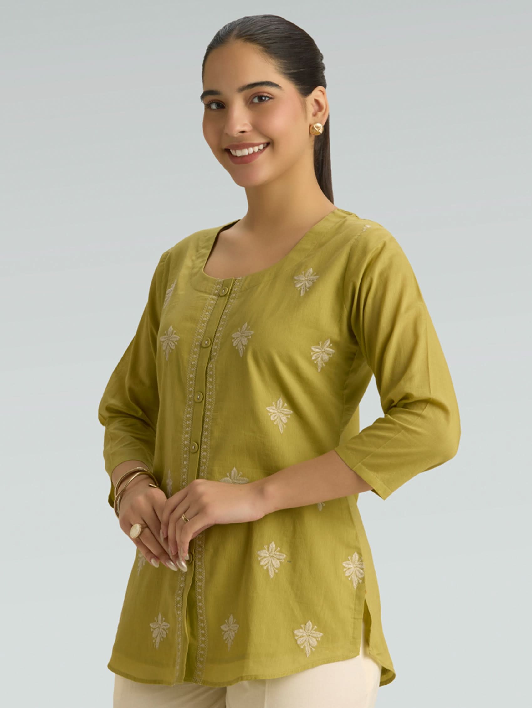 Woman wearing a green top with a plain background