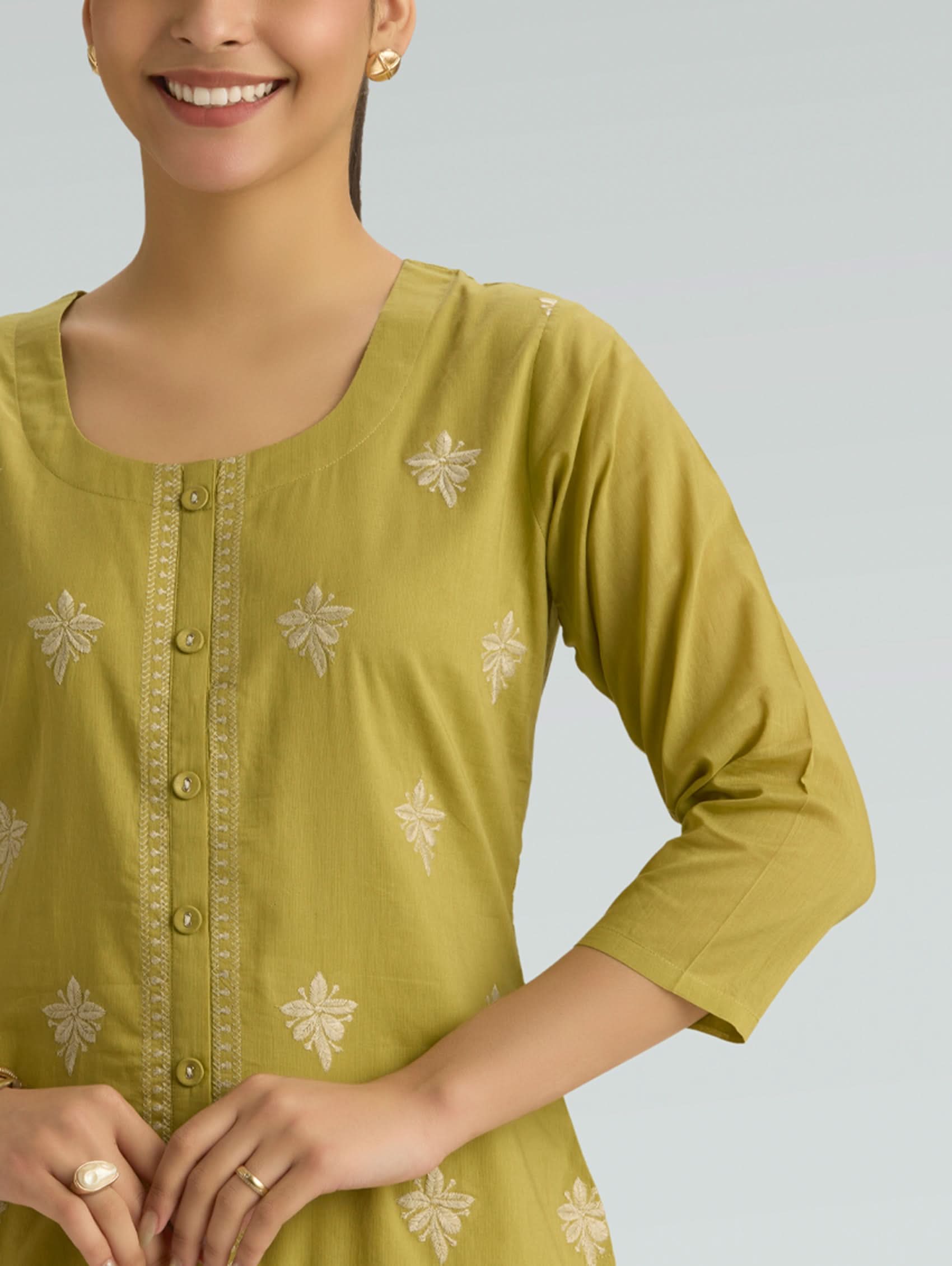Woman wearing a green top with a plain background