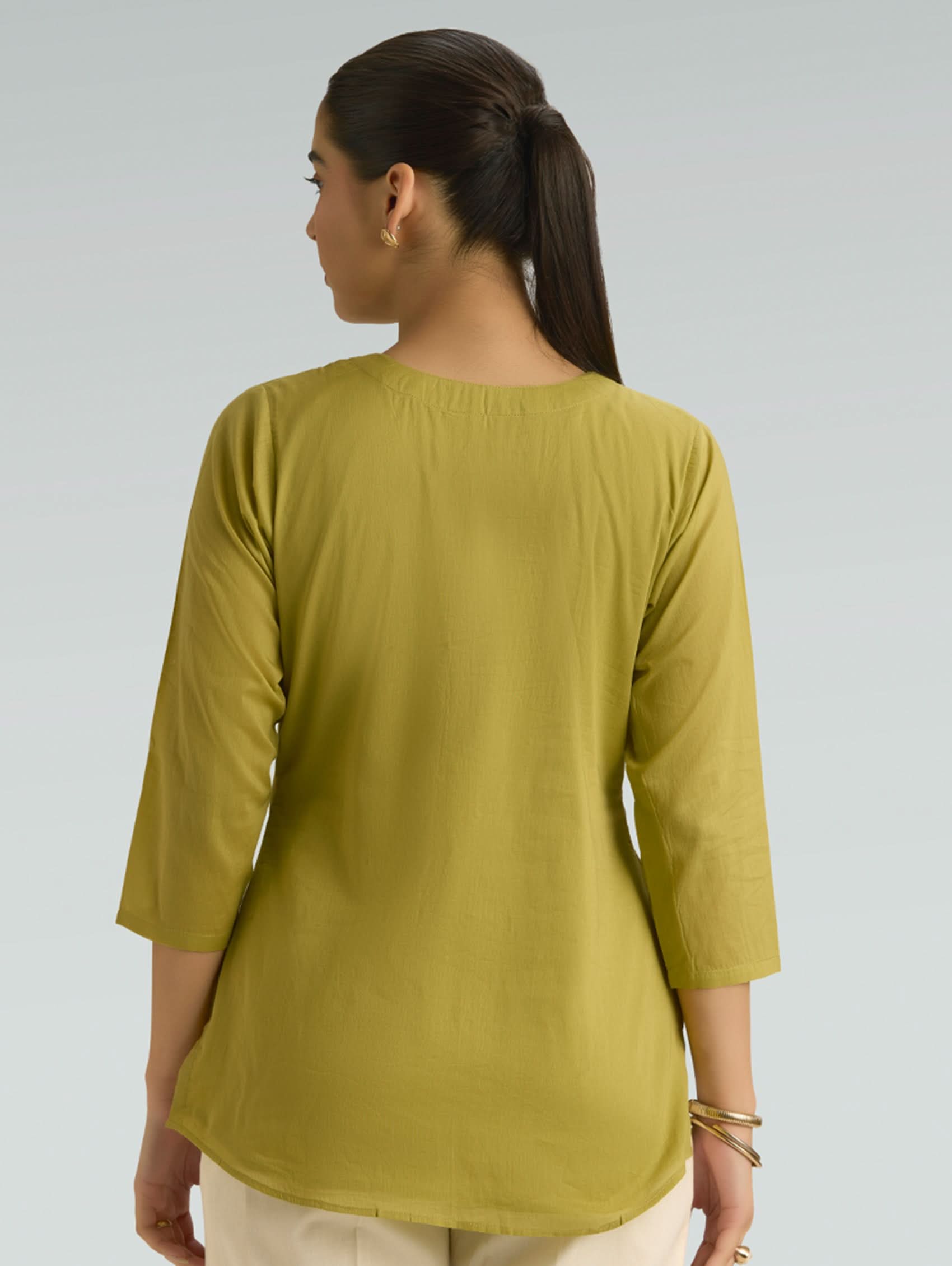 Woman wearing a green top with a plain background
