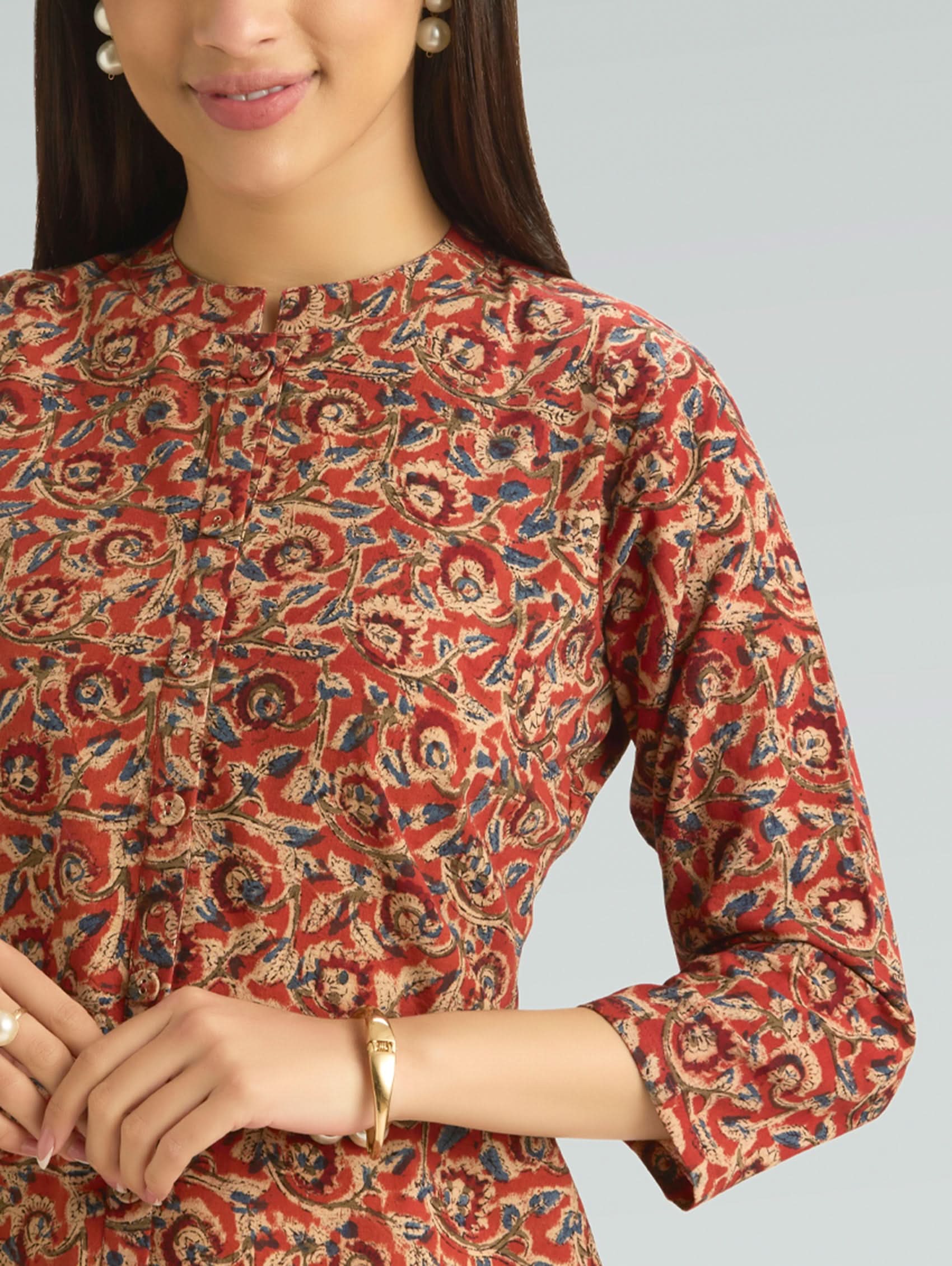 Person wearing a red patterned top on a gray background