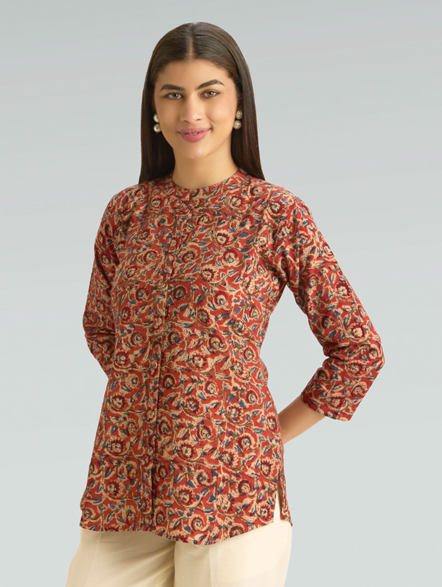 Woman wearing a red patterned long-sleeve top against a gray background