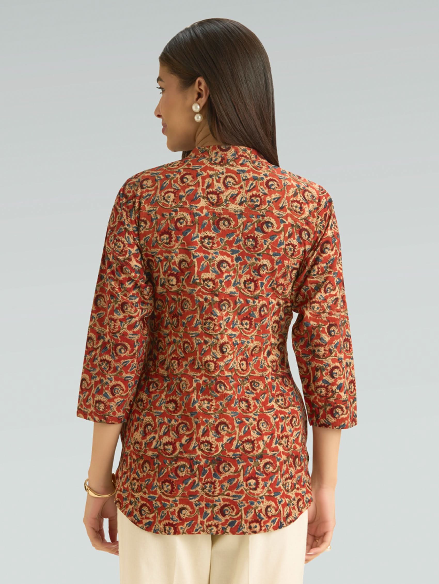 Woman wearing a patterned red and orange shirt on a gray background