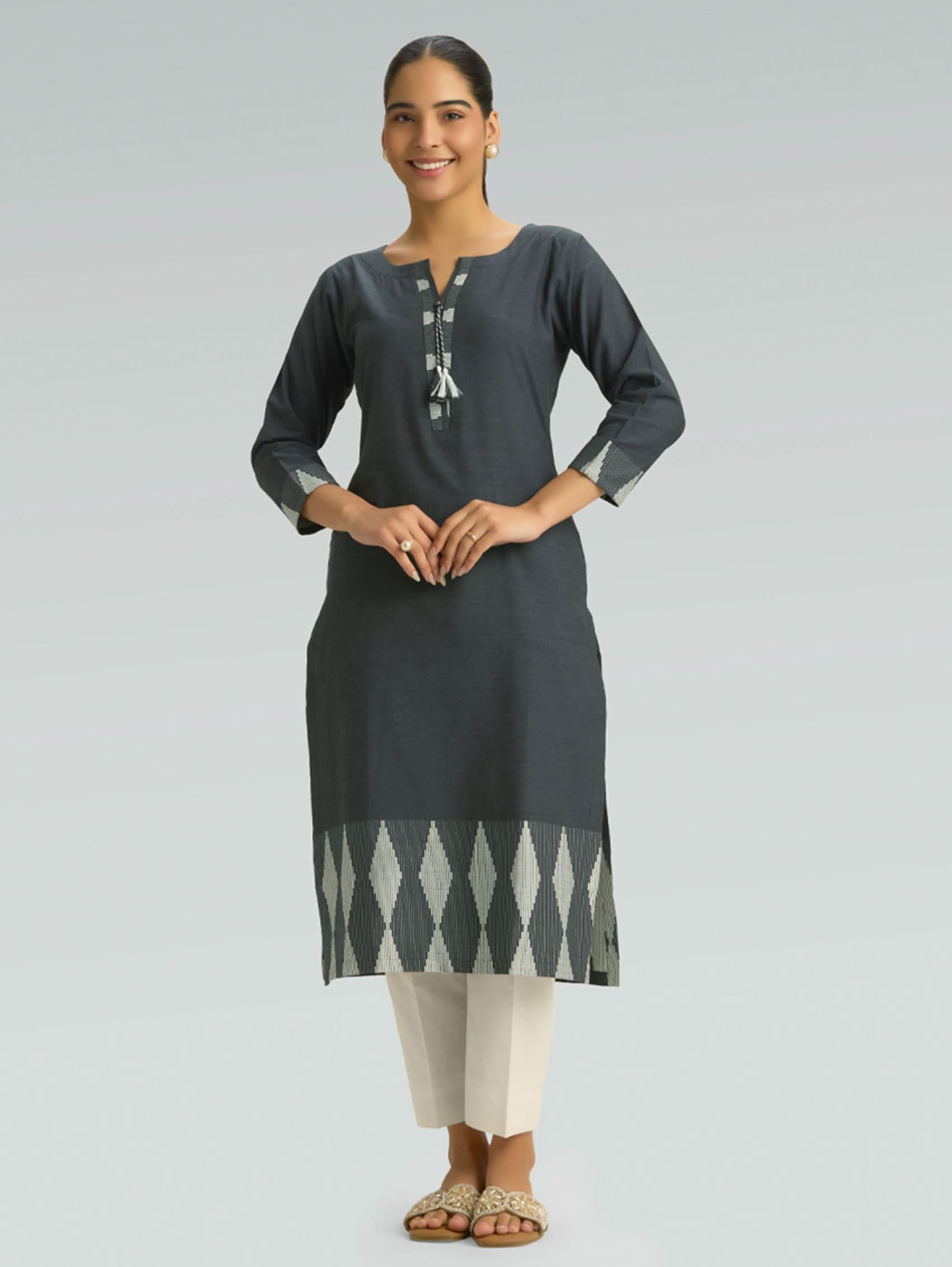 Woman wearing a dark gray kurta with white patterns on a light gray background