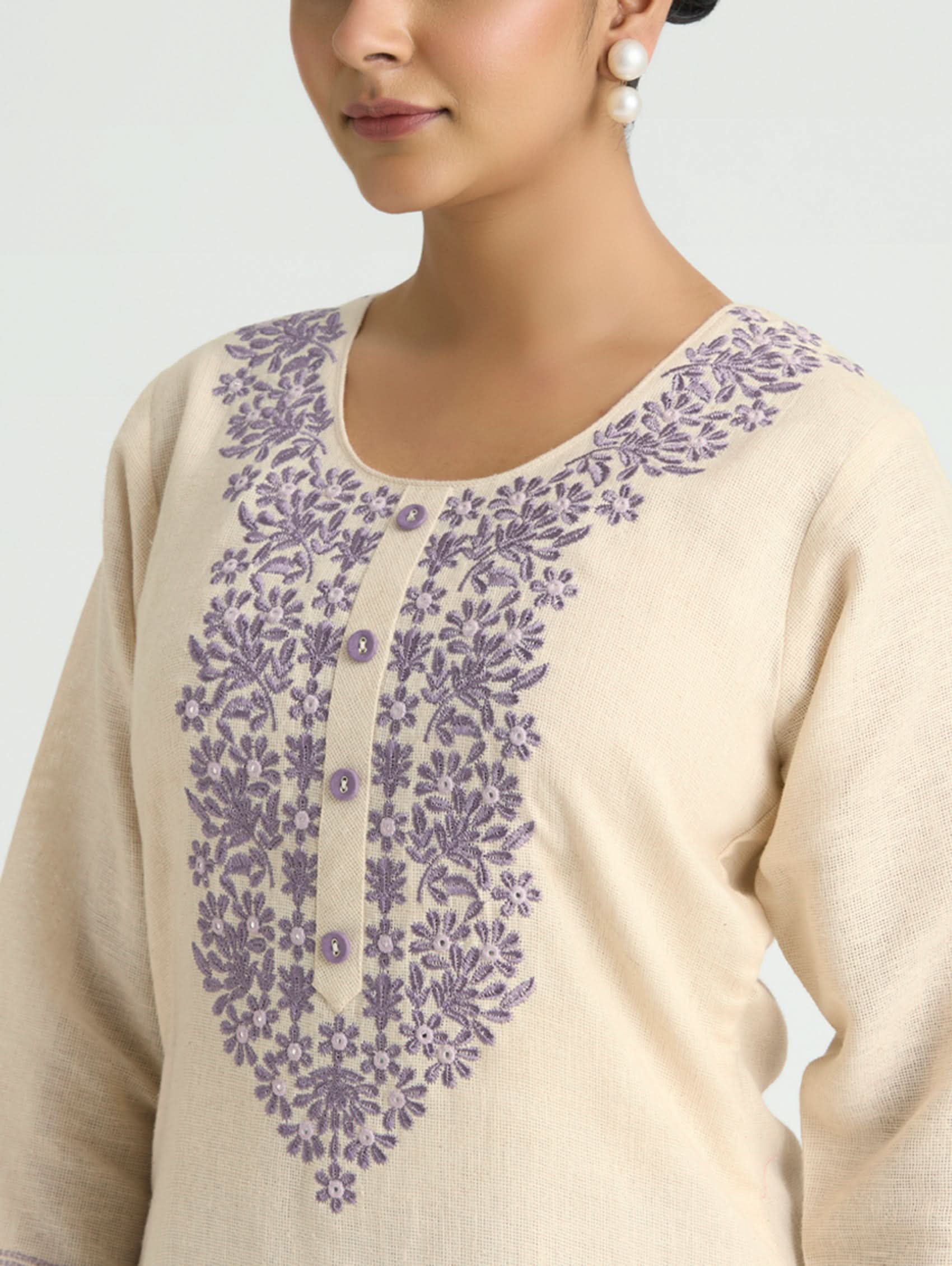 Beige kurta with purple floral embroidery on a plain background