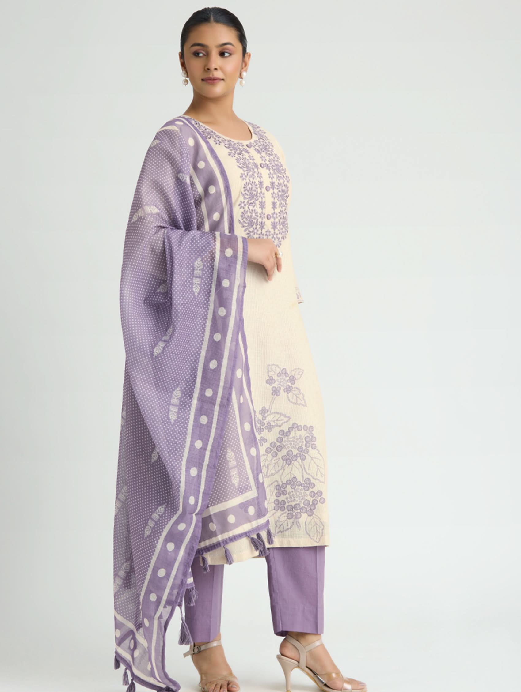 Woman wearing a lavender and white traditional outfit on a light gray background