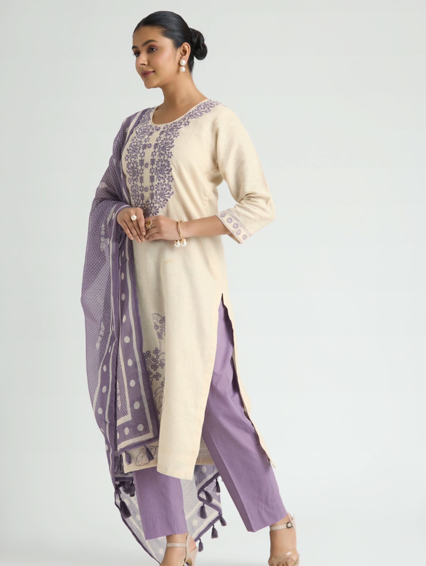 Woman wearing a cream and purple traditional outfit on a light gray background