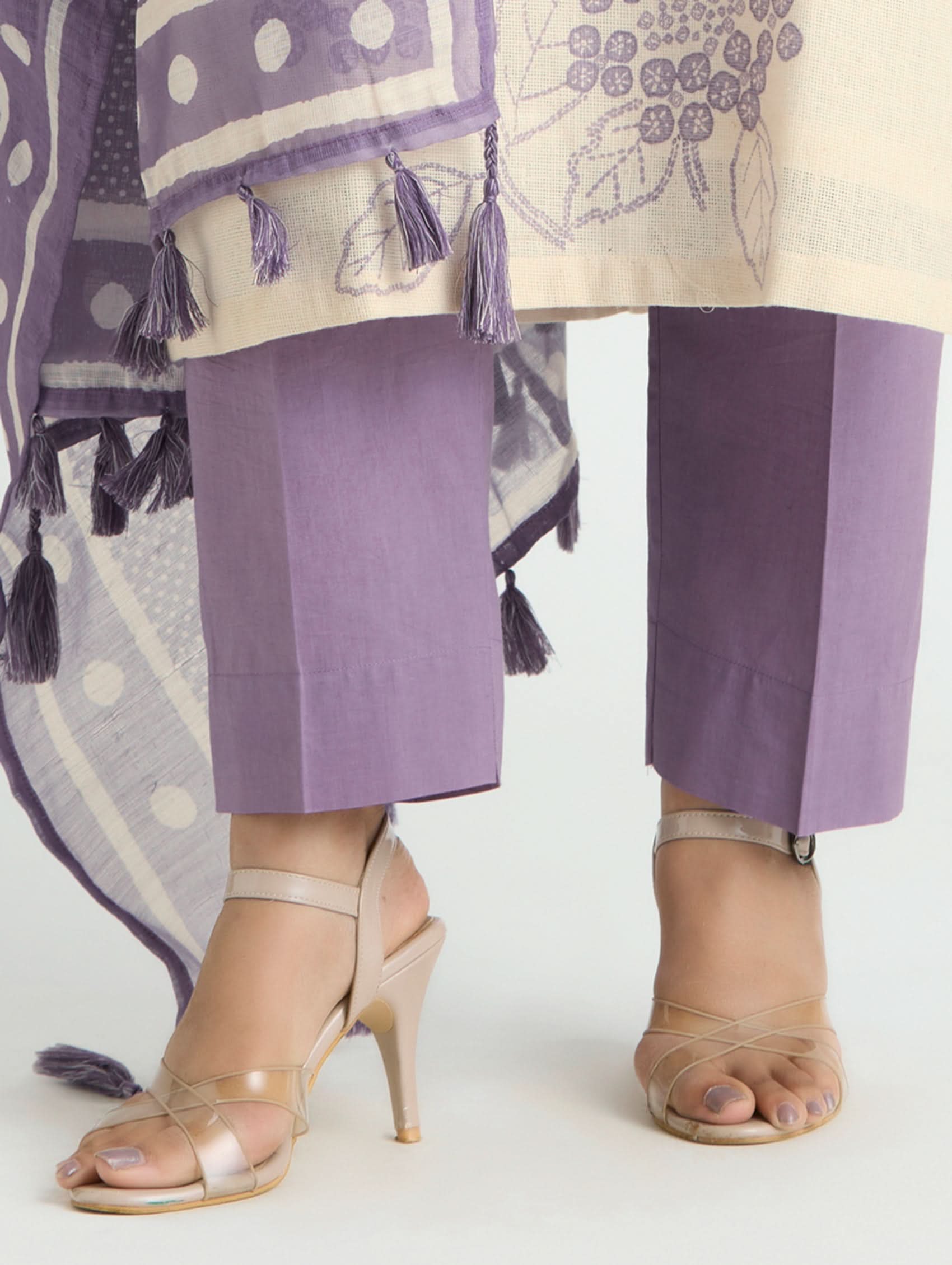 Purple pants with white polka dots and tassels, beige high-heeled sandals on a white background