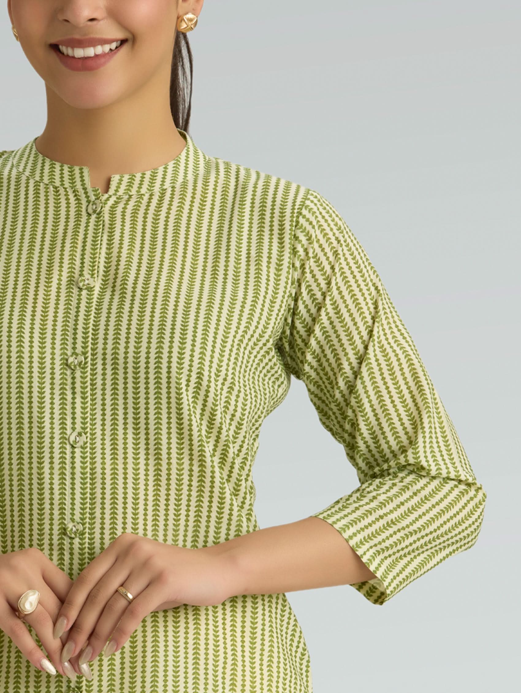 Woman wearing a green and white patterned shirt against a gray background