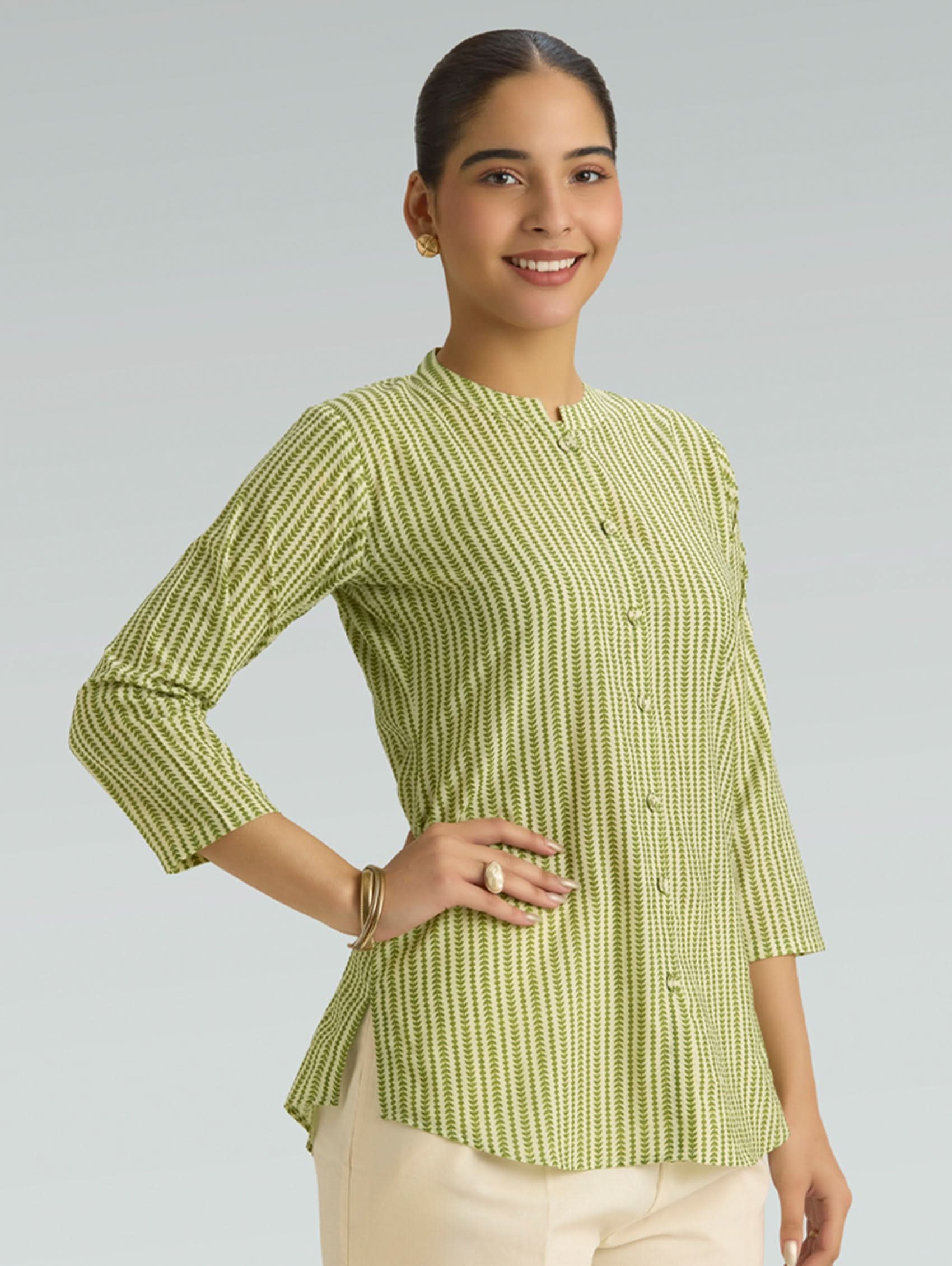 Woman wearing a green patterned top against a plain background