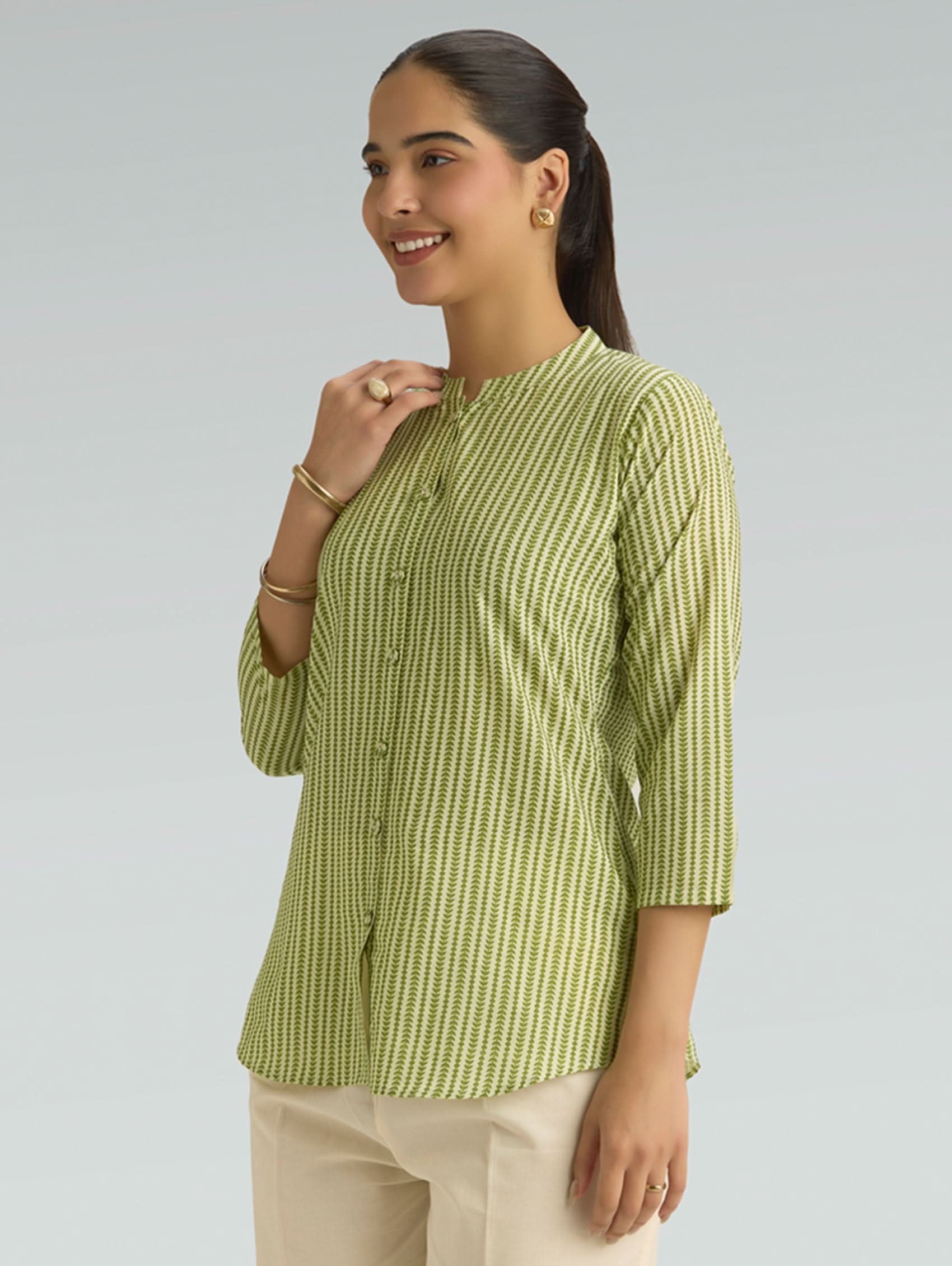 Woman wearing a green and white striped shirt against a gray background