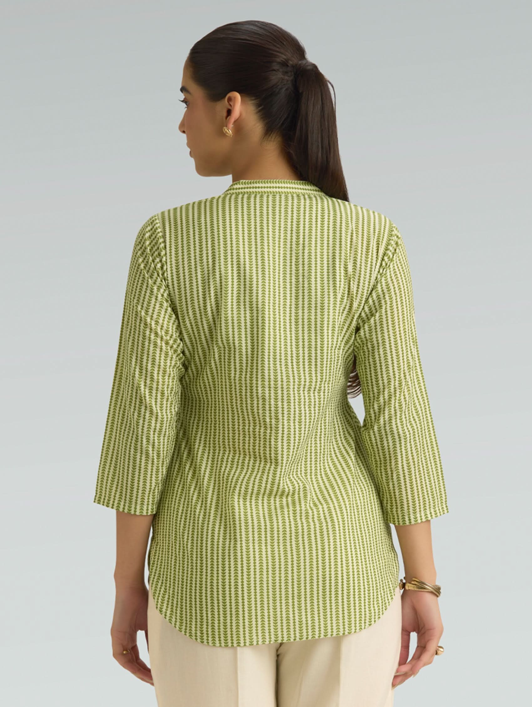 Woman wearing a green checkered top against a gray background