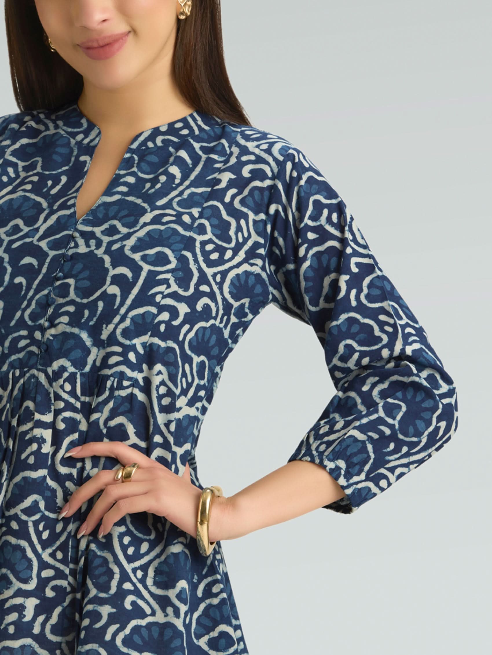 Woman wearing a blue patterned dress on a gray background