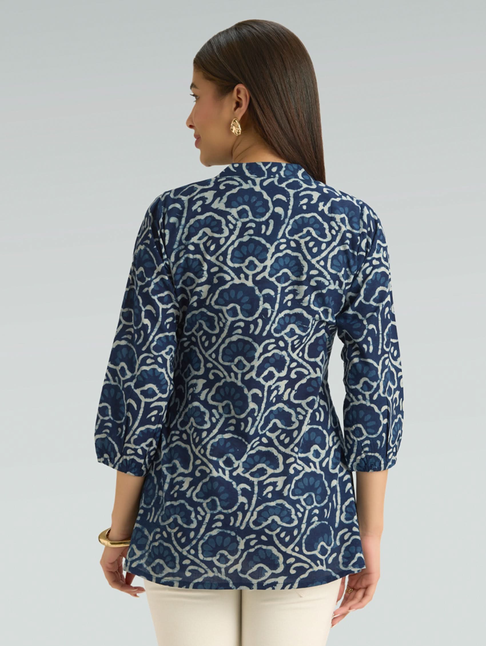 Woman wearing a blue patterned shirt on a gray background