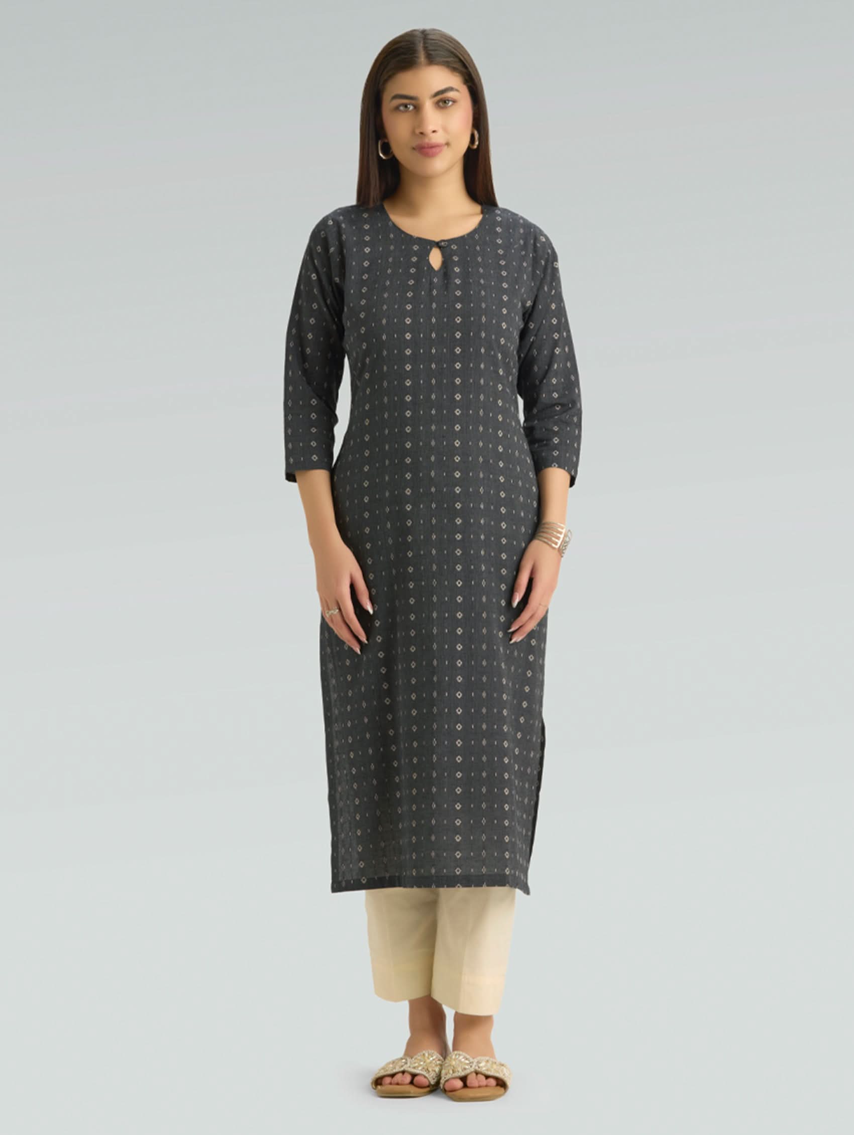 Woman wearing a dark grey patterned kurta with side slit and beige pants on a light grey background