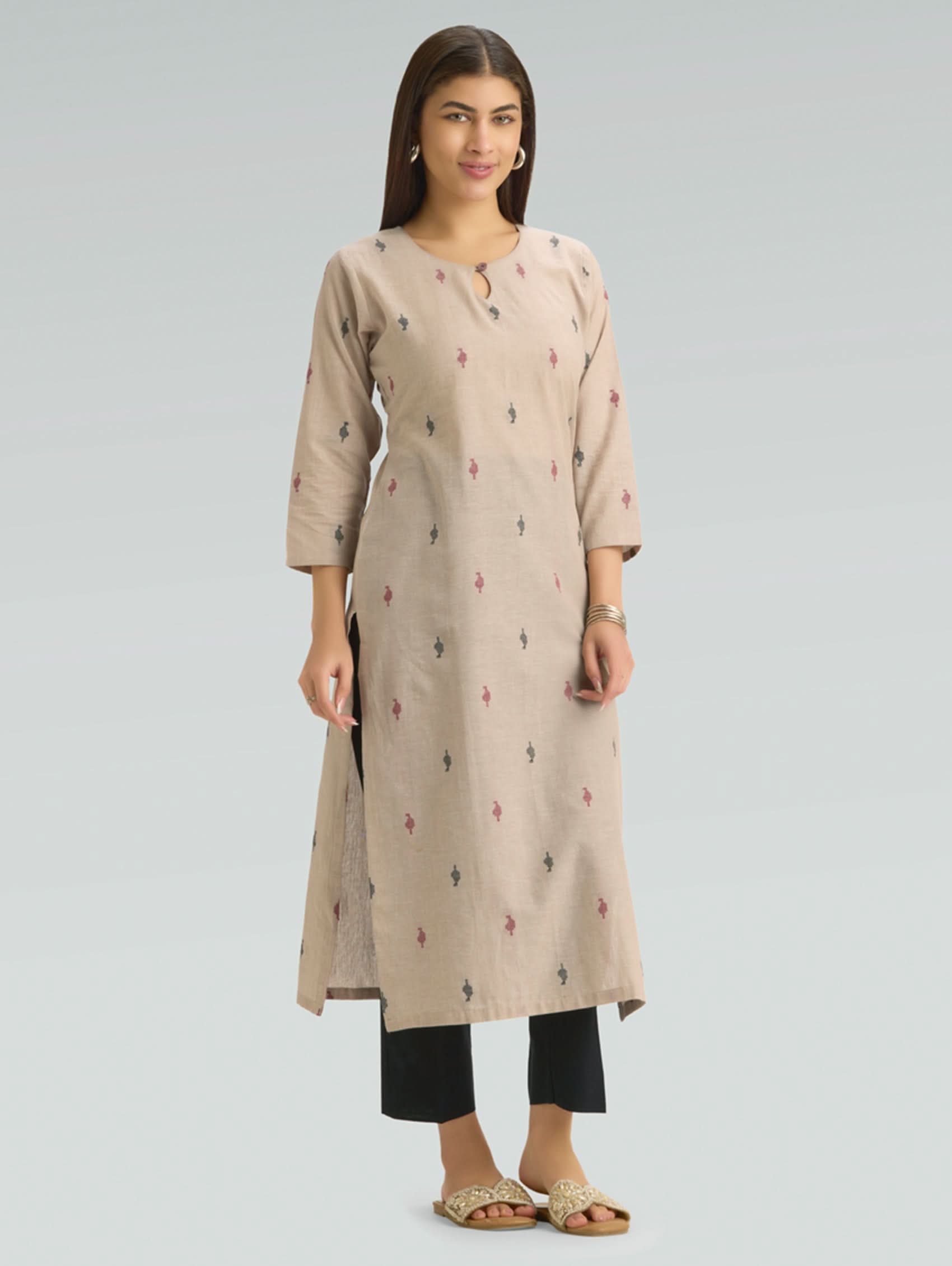 Woman wearing a beige kurta with black pants on a gray background