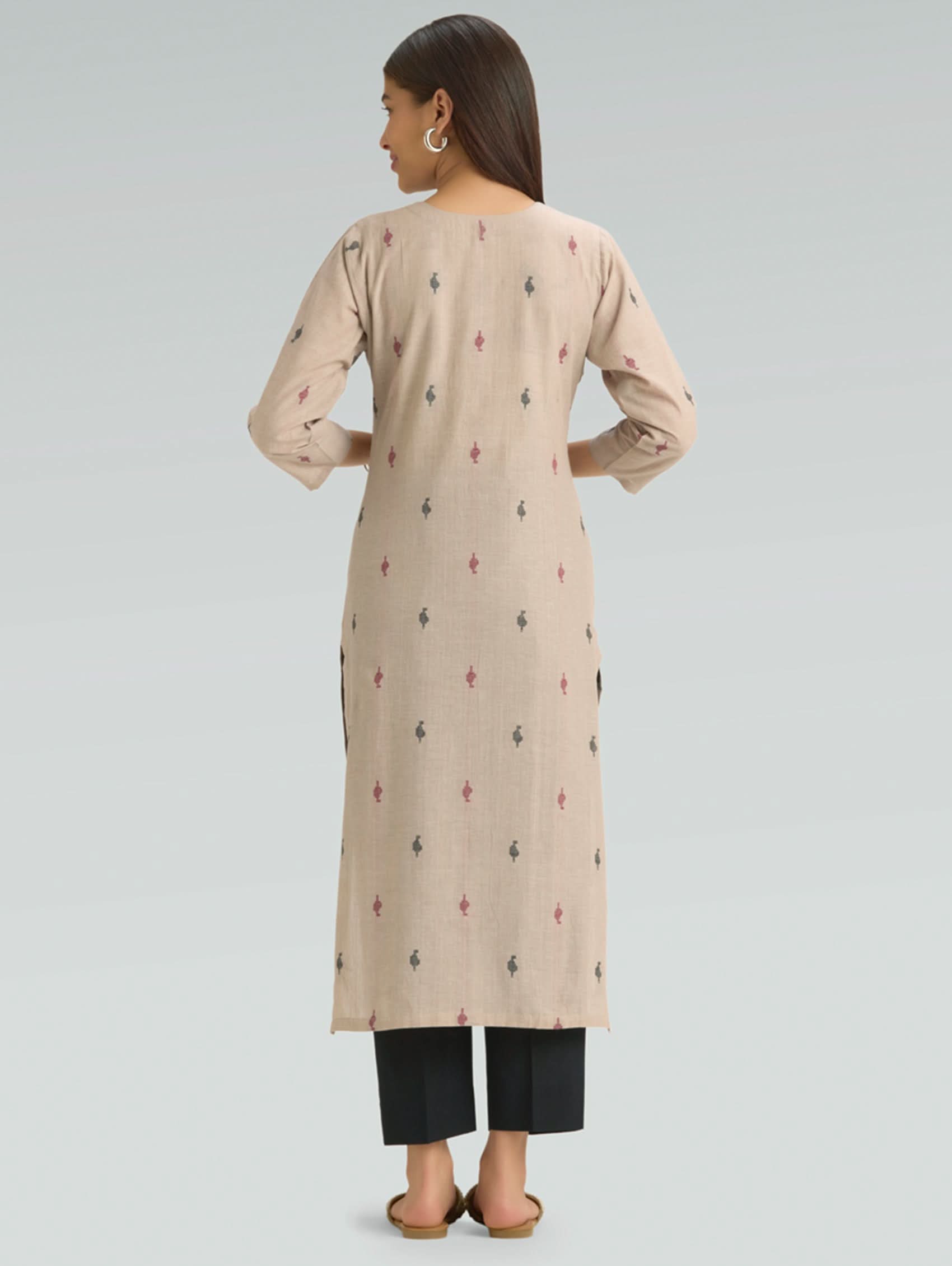 Woman wearing a beige long kurta with black patterns on a light gray background