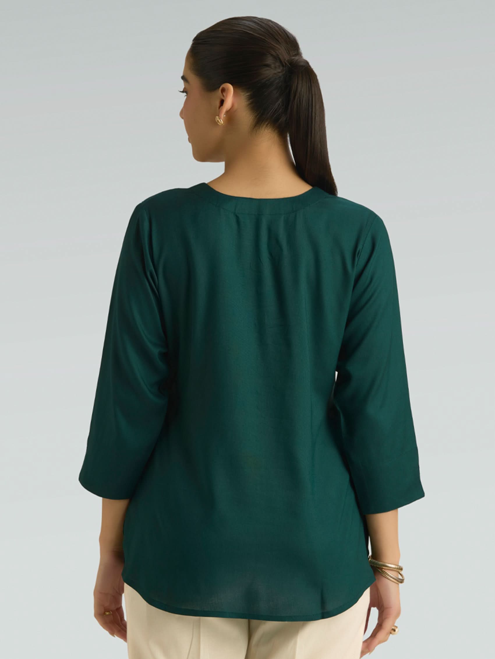 Woman wearing a green top with a plain background