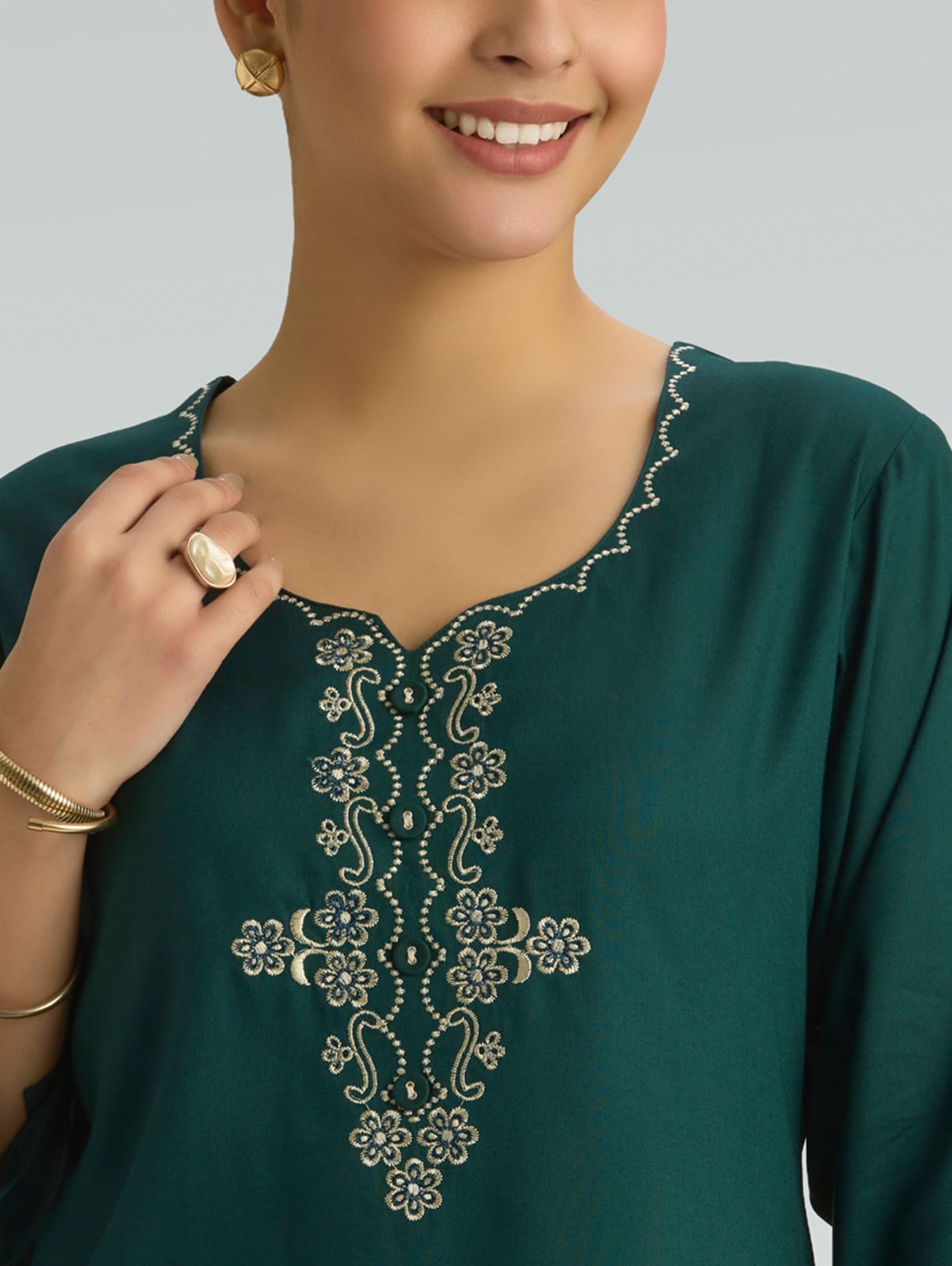 Green embroidered top worn by a person on a gray background